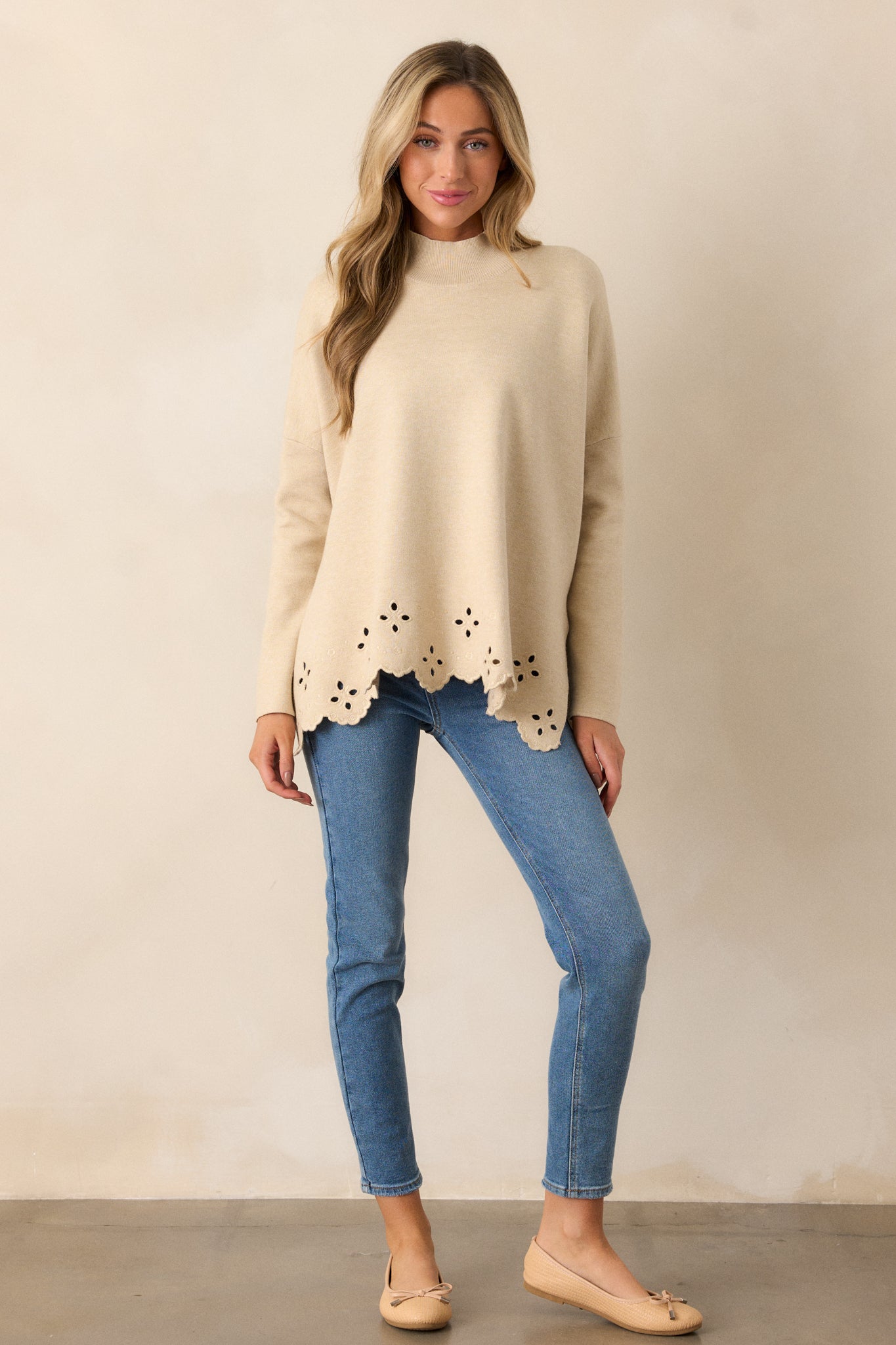 A full-body shot of the sweater, focusing on the long sleeves and the boxy silhouette with the eyelet detail at the bottom.