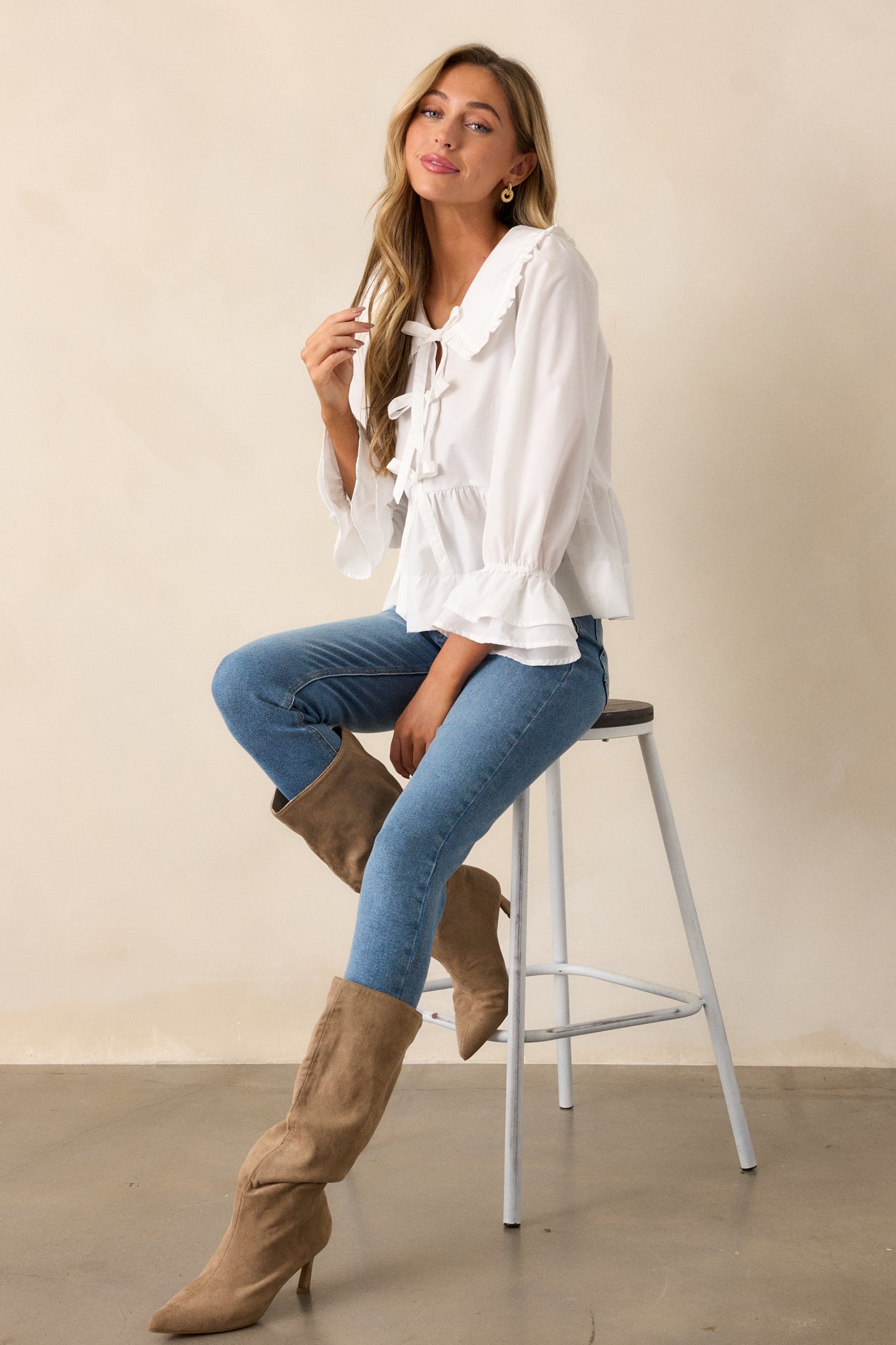 A full-length shot highlighting the ruffled collar neckline and bow accents on the front of the blouse.