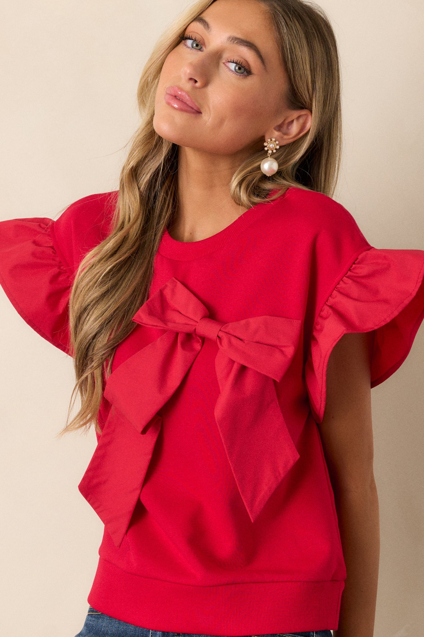 Close-up of the red top’s crew neckline and bow detail, highlighting the fabric and neat stitching.