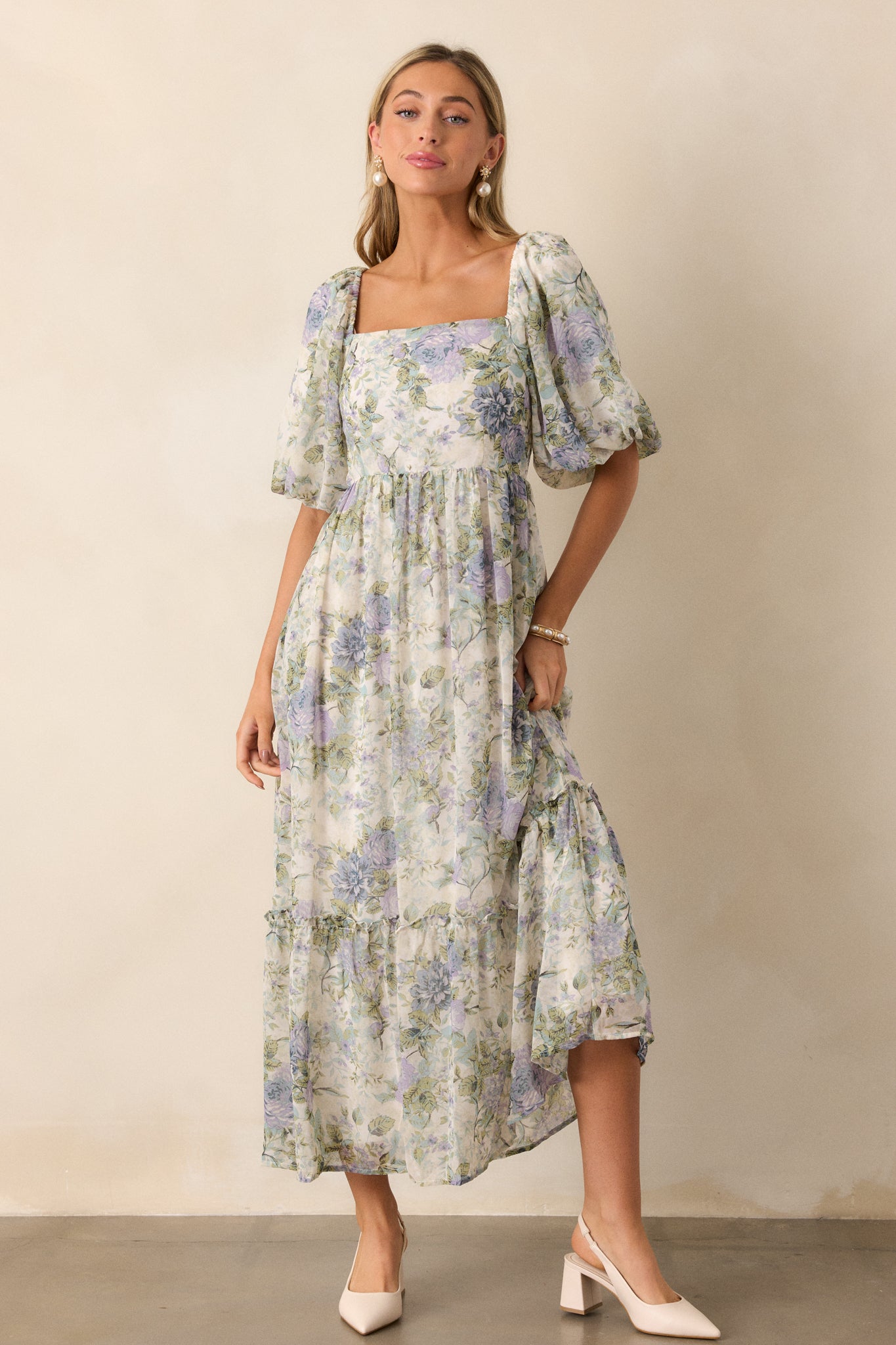 A full body view of the ivory dress displaying the square neckline and delicate floral pattern, with puff sleeves that enhance the dress's romantic look.