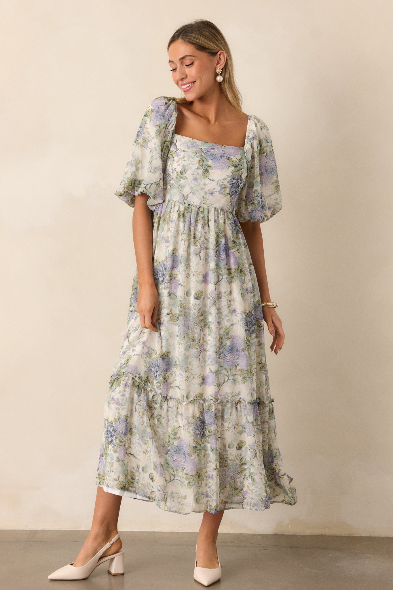 A full body image from a slightly elevated angle, showcasing the overall silhouette of the dress, including the floral pattern and the tiered design.