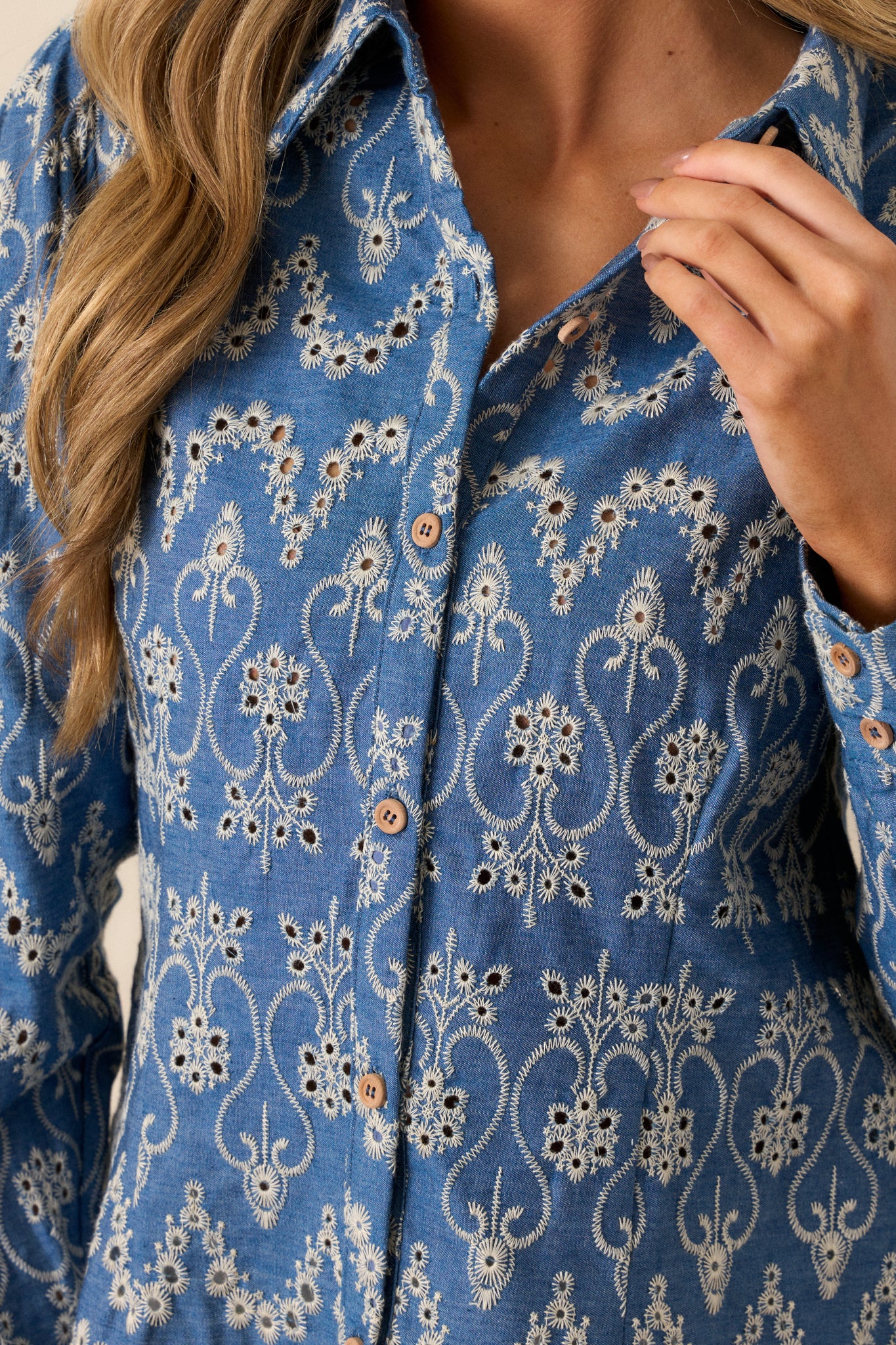 A close-up of the fabric texture, highlighting the embroidery and eyelet detailing that adds elegance to the blue top.