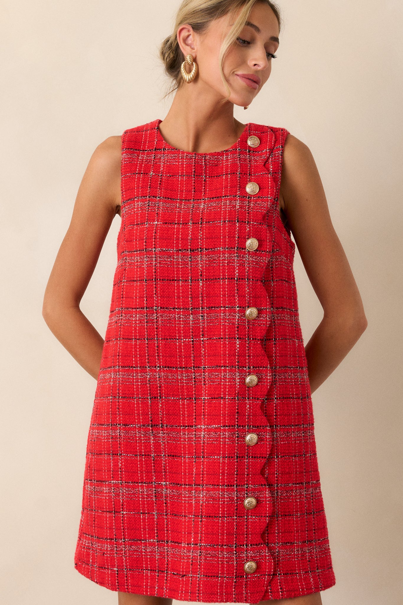 Close-up of the plaid tweed fabric of the red dress, highlighting the intricate gold detailing and rich texture.