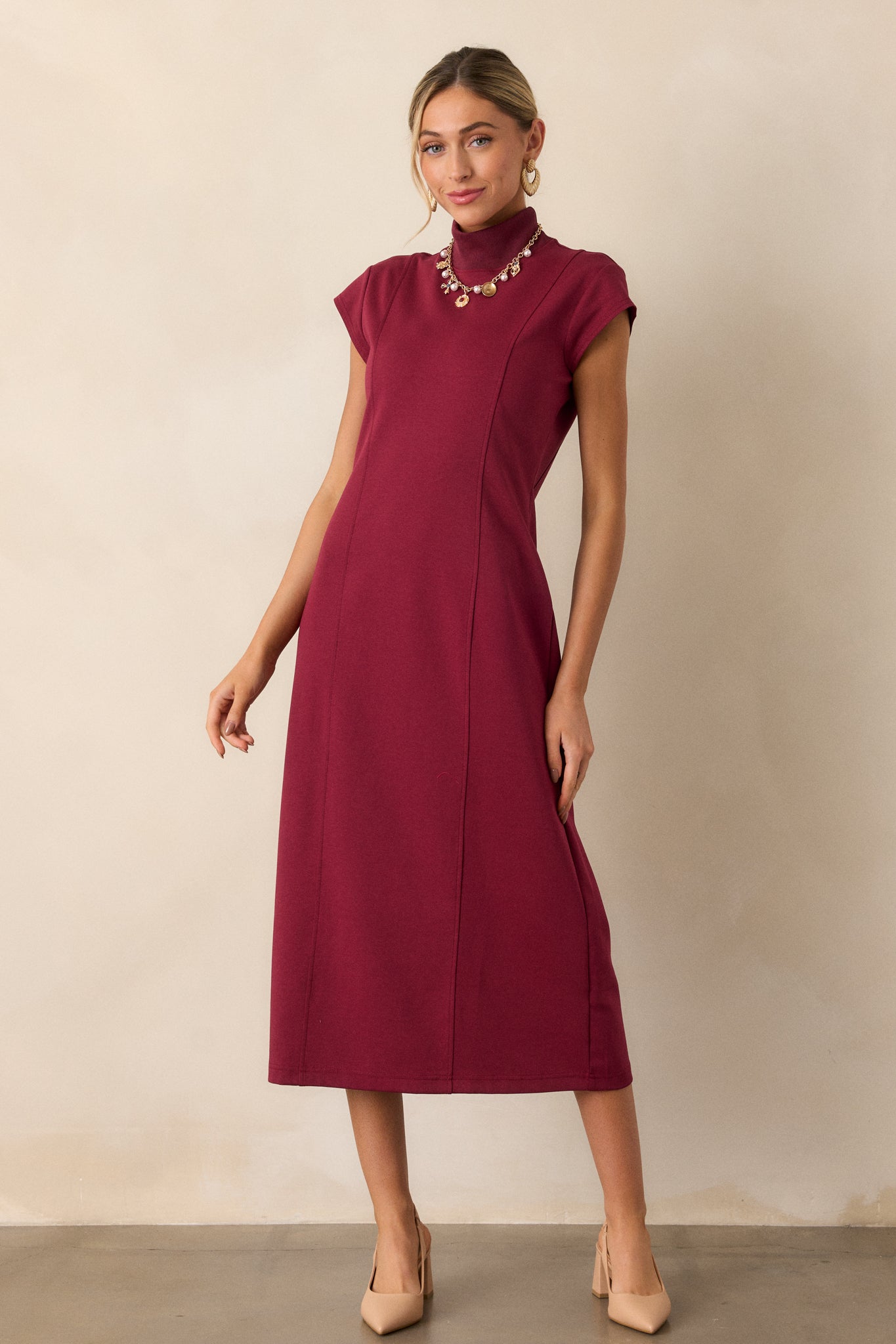 The burgundy dress displayed in full view, highlighting the slight cap sleeves and the flattering contouring effect created by the princess seams.