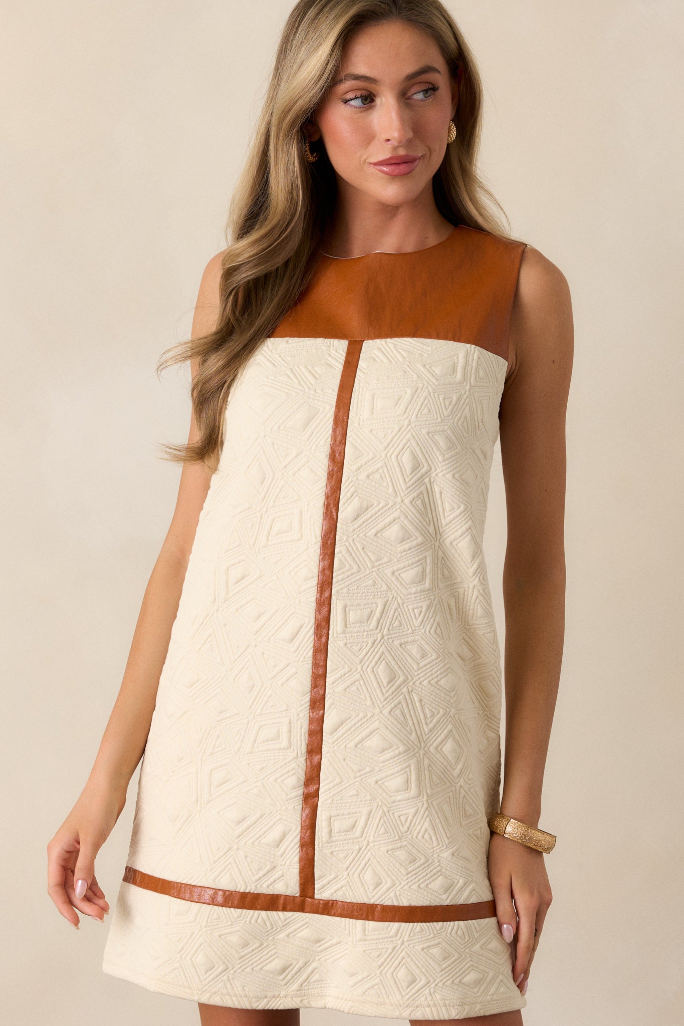 Mid-shot of the dress's faux brown leather yolk and quilted ivory fabric, focusing on the texture and design details.