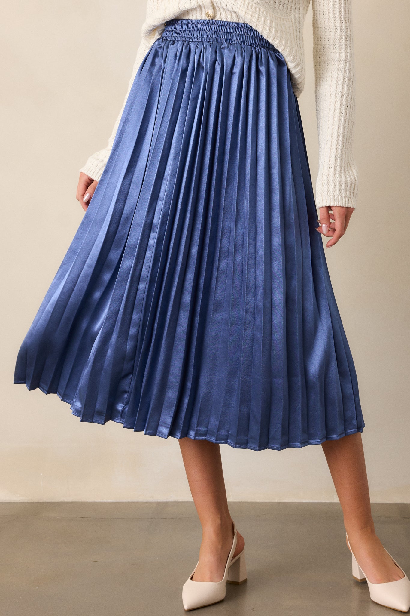 View of the lower half of the skirt, focusing on the delicate pleating and flow of the fabric as it cascades to the midi length.