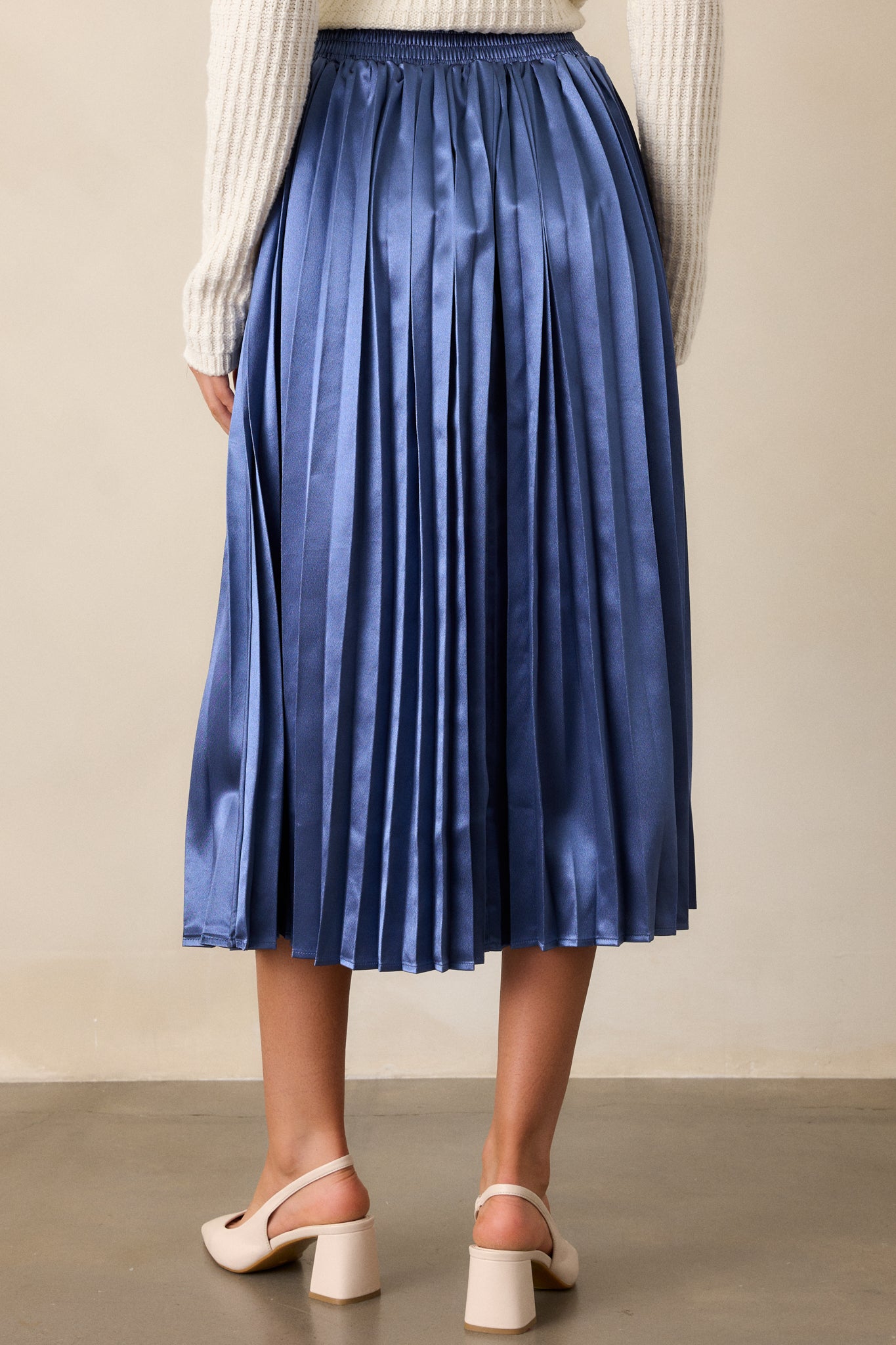 Back view of the skirt, displaying the clean lines of the pleated fabric and the elastic waistband, with no visible seams or distractions.