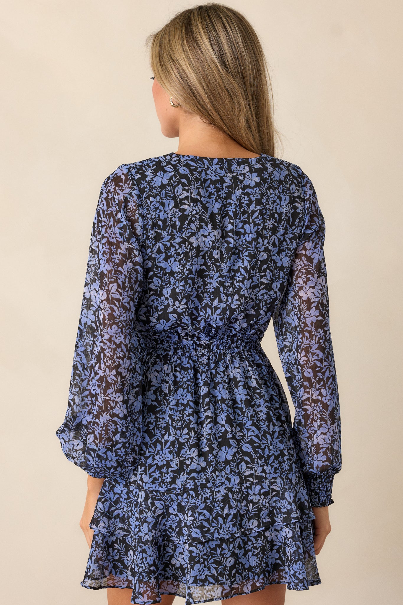 Full back view of the midnight blue dress, emphasizing the long sleeves, cinched waist, and the movement of the tulip-shaped skirt.