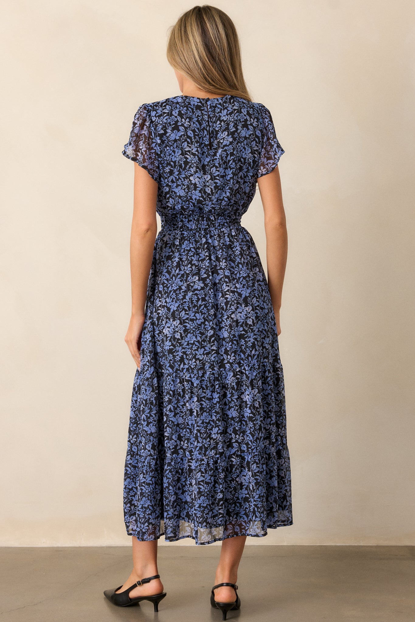 Back view of the midnight blue dress, highlighting the short sleeves, tiered skirt, and the flowy silhouette created by the self-tie waistband.