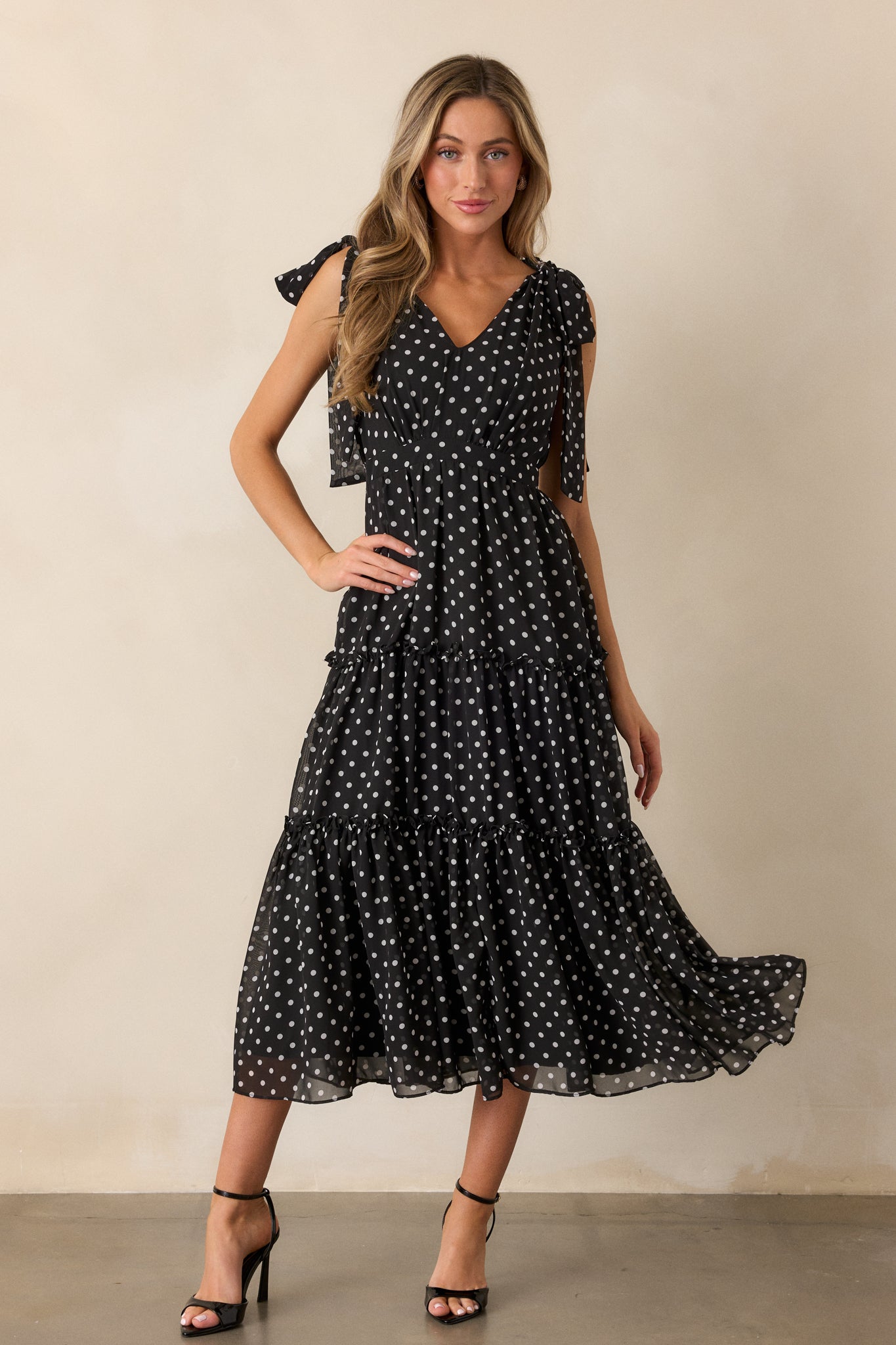 Front view of the dress, showcasing the v-neckline, polka dot print, and the tiered skirt with ruffled hems. The self-tie sleeves add a delicate touch to the design.