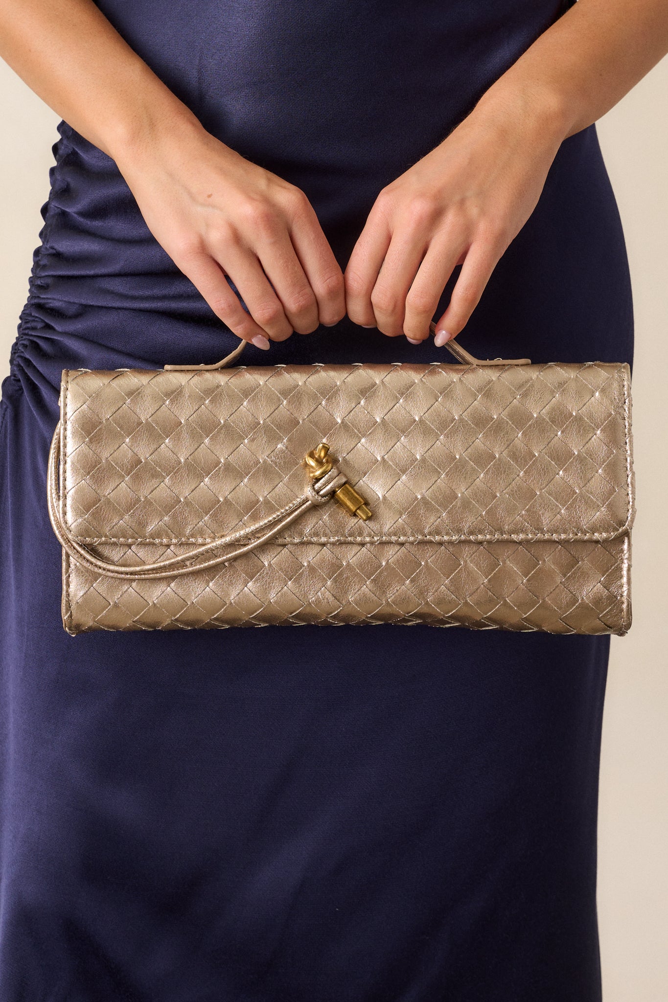  Close-up of the top handle of the gold handbag, focusing on the gold handle and the magnetic fold-over closure.