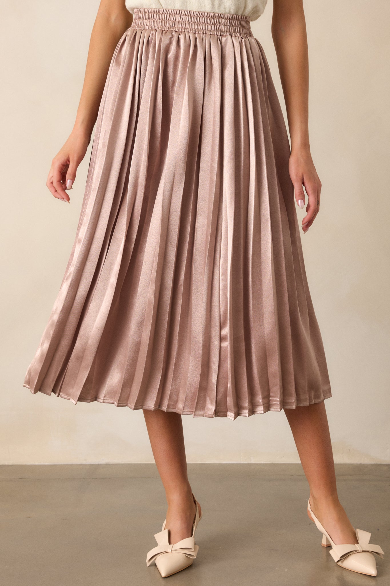 A cropped shot of the rose gold skirt's pleated fabric, emphasizing the shimmering pleats and soft flow.