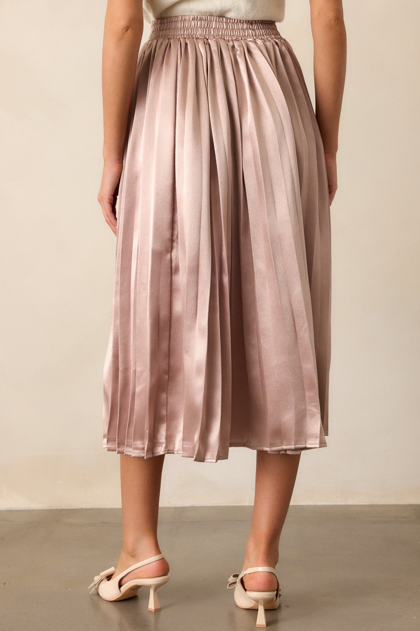 A back view of the skirt, displaying the full length of the pleats and the elastic waistband, emphasizing its sleek, smooth silhouette.