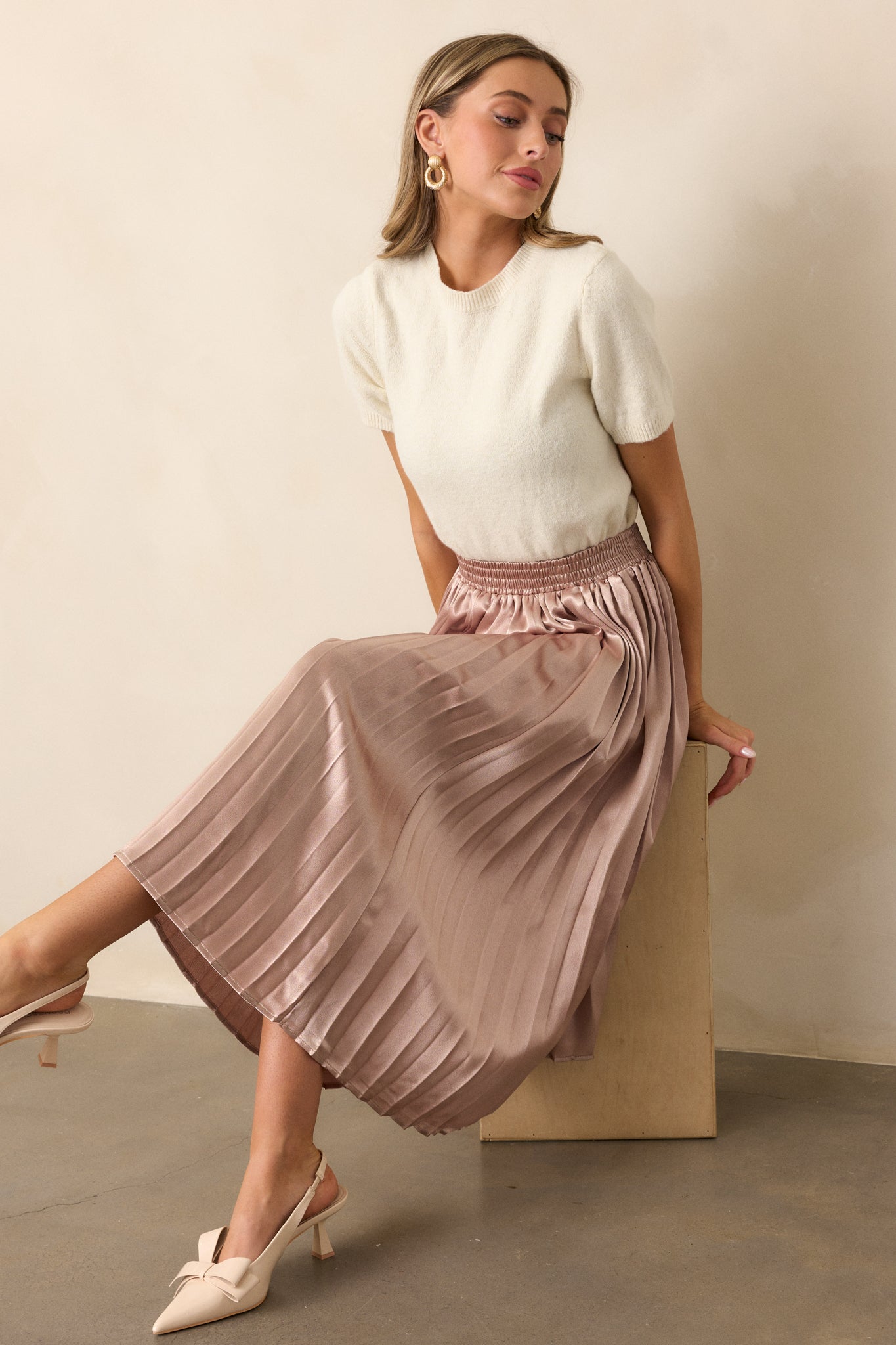 A side view of the rose gold skirt, highlighting the pleated texture and midi length, paired with the elastic waistband.