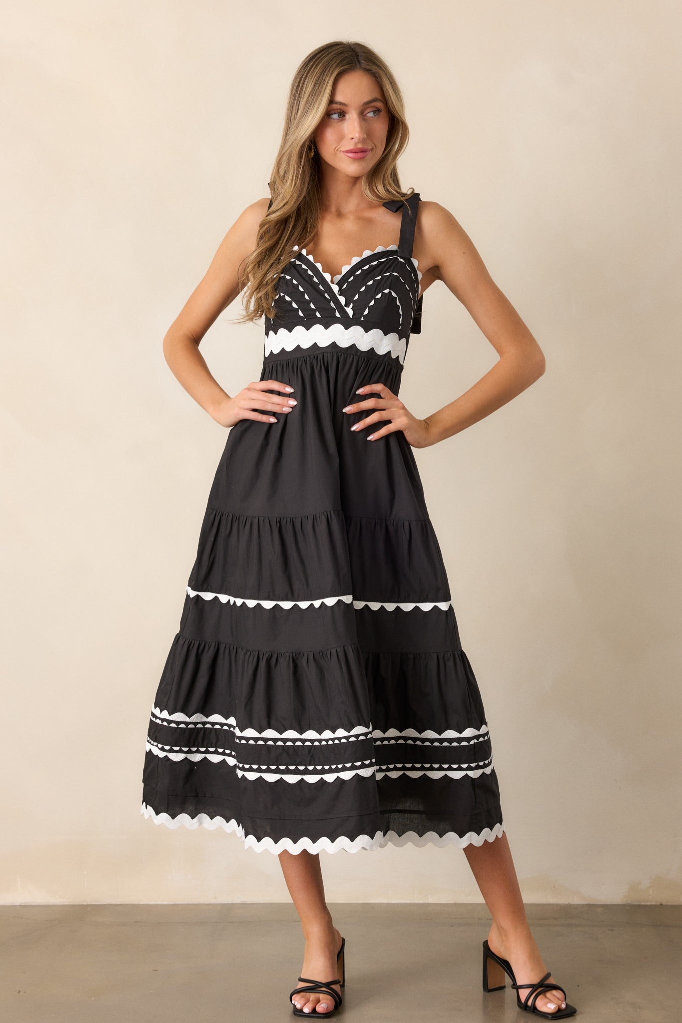 A front view of the black maxi dress, highlighting the v-neckline, thick self-tie straps, and tiers with ricrac detailing down the skirt.