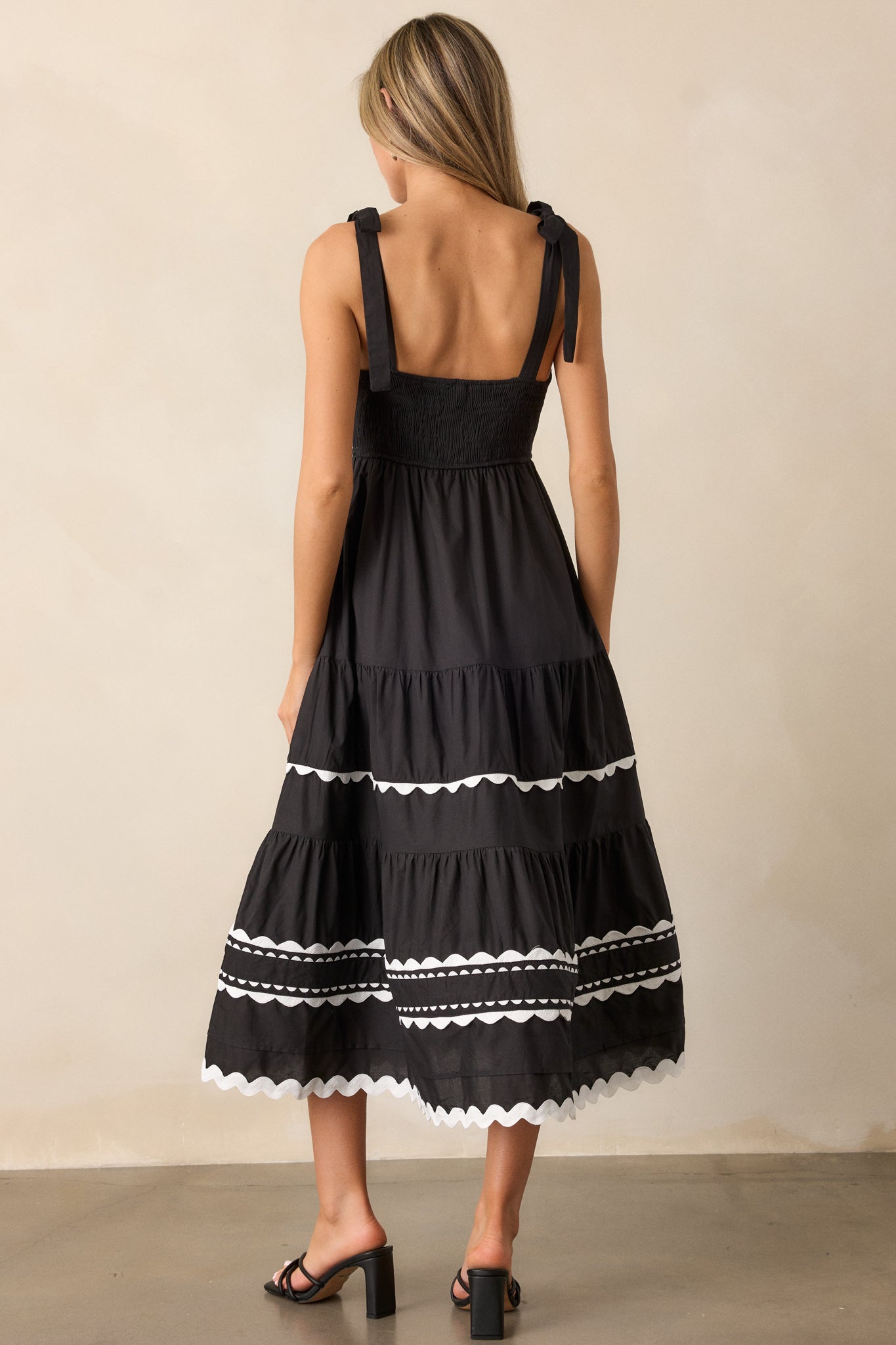 A back view of the dress, showing the fully smocked back and how the self-tie straps attach to the back. The ricrac trim along the waistband and hemline is also visible.