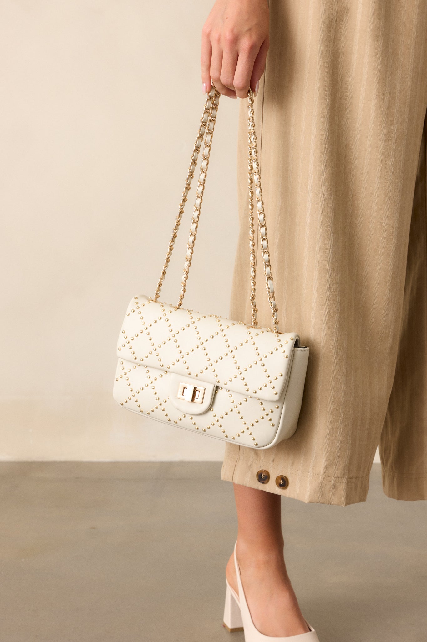 Another full view of the handbag from a different angle, highlighting the braided chain handles and gold-studded quilted texture.