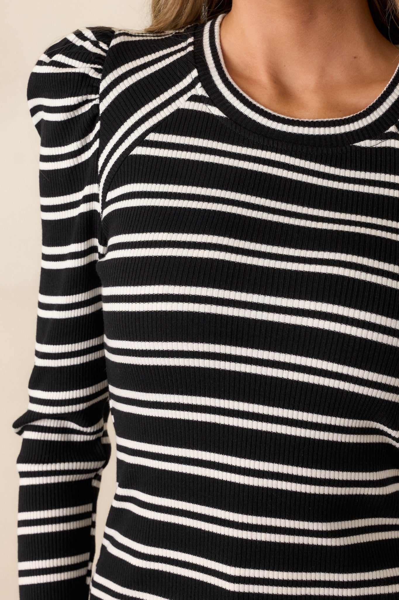 Zoomed-in shot of the neckline and upper chest area, showcasing the rounded neckline and the start of the white stripe pattern on the ribbed knit fabric.