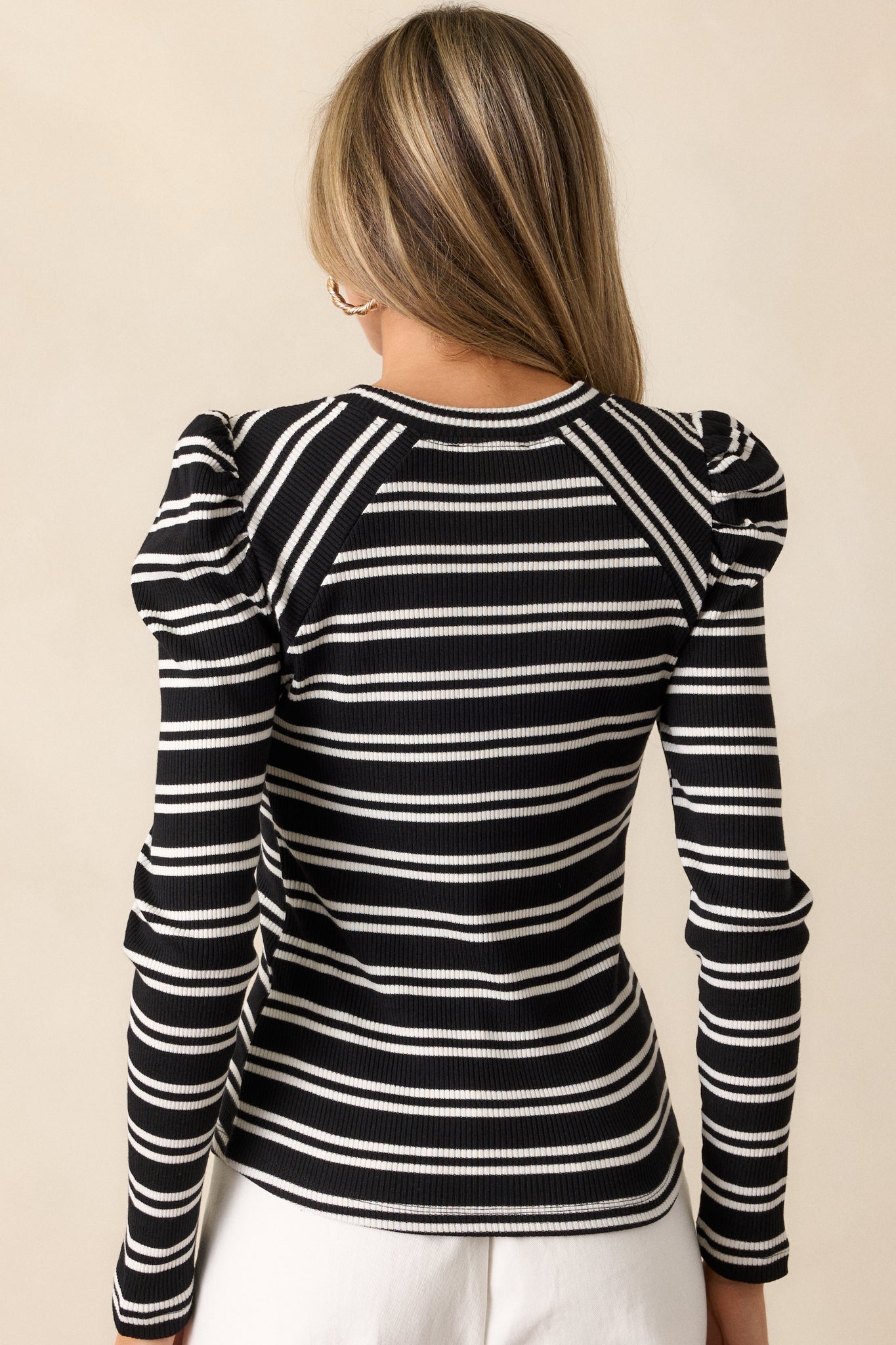 Back view of the top, showing the continuation of the white stripe pattern on the ribbed knit fabric and the fitted design on the back.