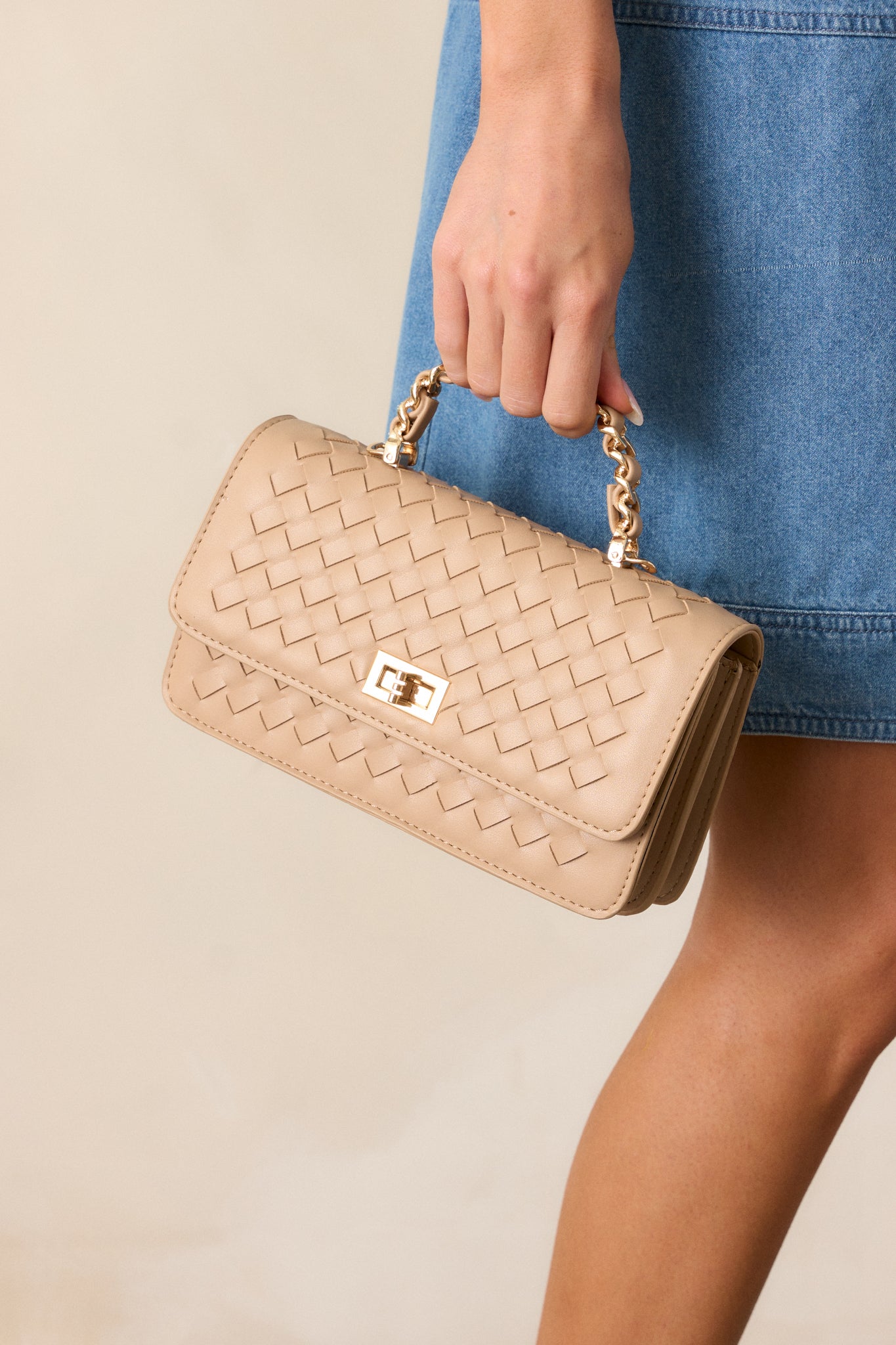 Side angle of the handbag, highlighting the woven texture, gold hardware, and the beige and gold chain woven handle on top.