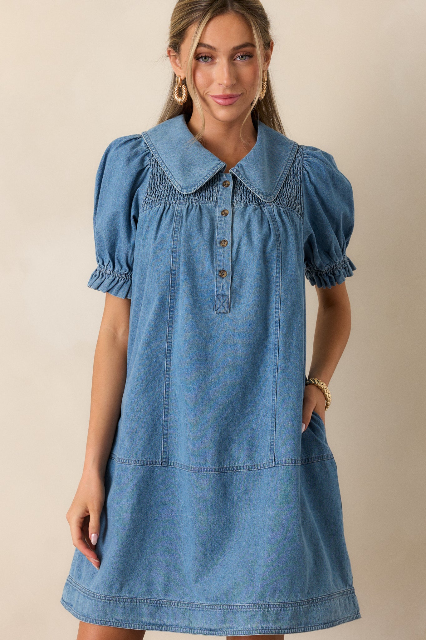 Close-up of the peter pan collar on the denim dress, highlighting the functional buttons and the smocked yolk detailing along the shoulders.