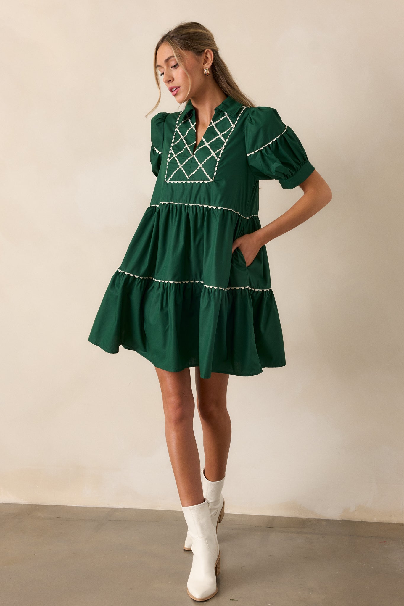 Full view of the emerald mini dress with a collared split neckline, tiered design, and white cross stitch yoke detailing.