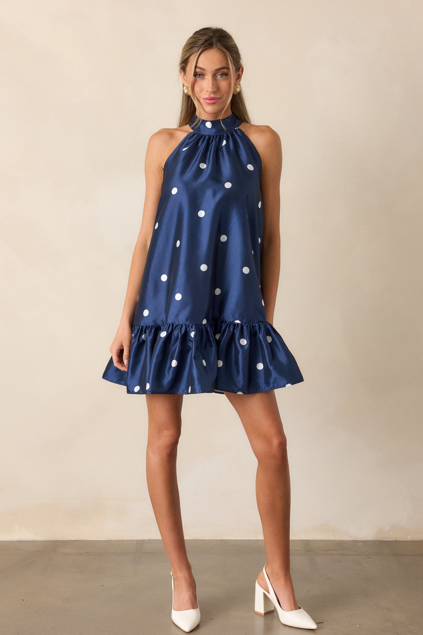 A complete front profile of the dress showing the flow of the babydoll cut and the ruffle bottom hem. The polka dot print adds texture and visual interest to the fabric.