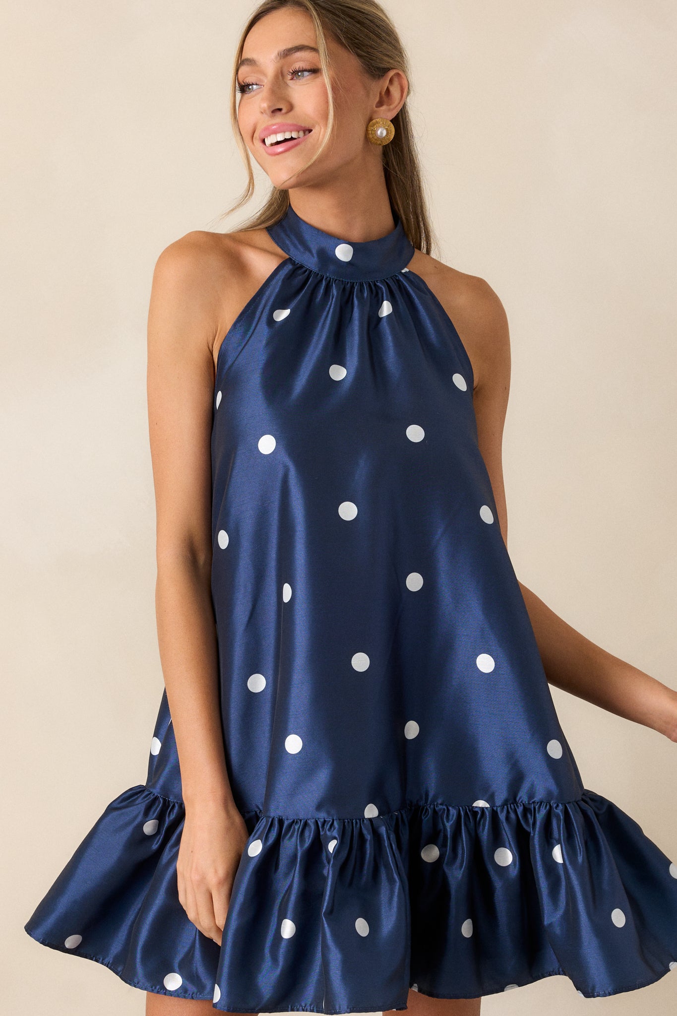 Another full-body view of the navy mini dress, highlighting the sleeveless design and the mini length. The ruffled hem and halter neckline with button clasps are clearly visible.