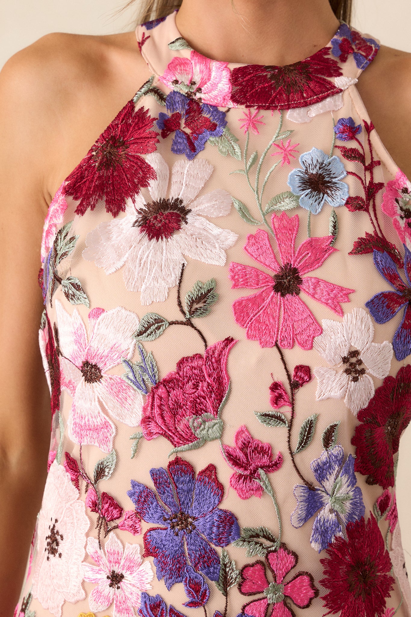 Close-up of the floral embroidered overlay, showing the detailed, textured design of the flowers against the fuchsia fabric.