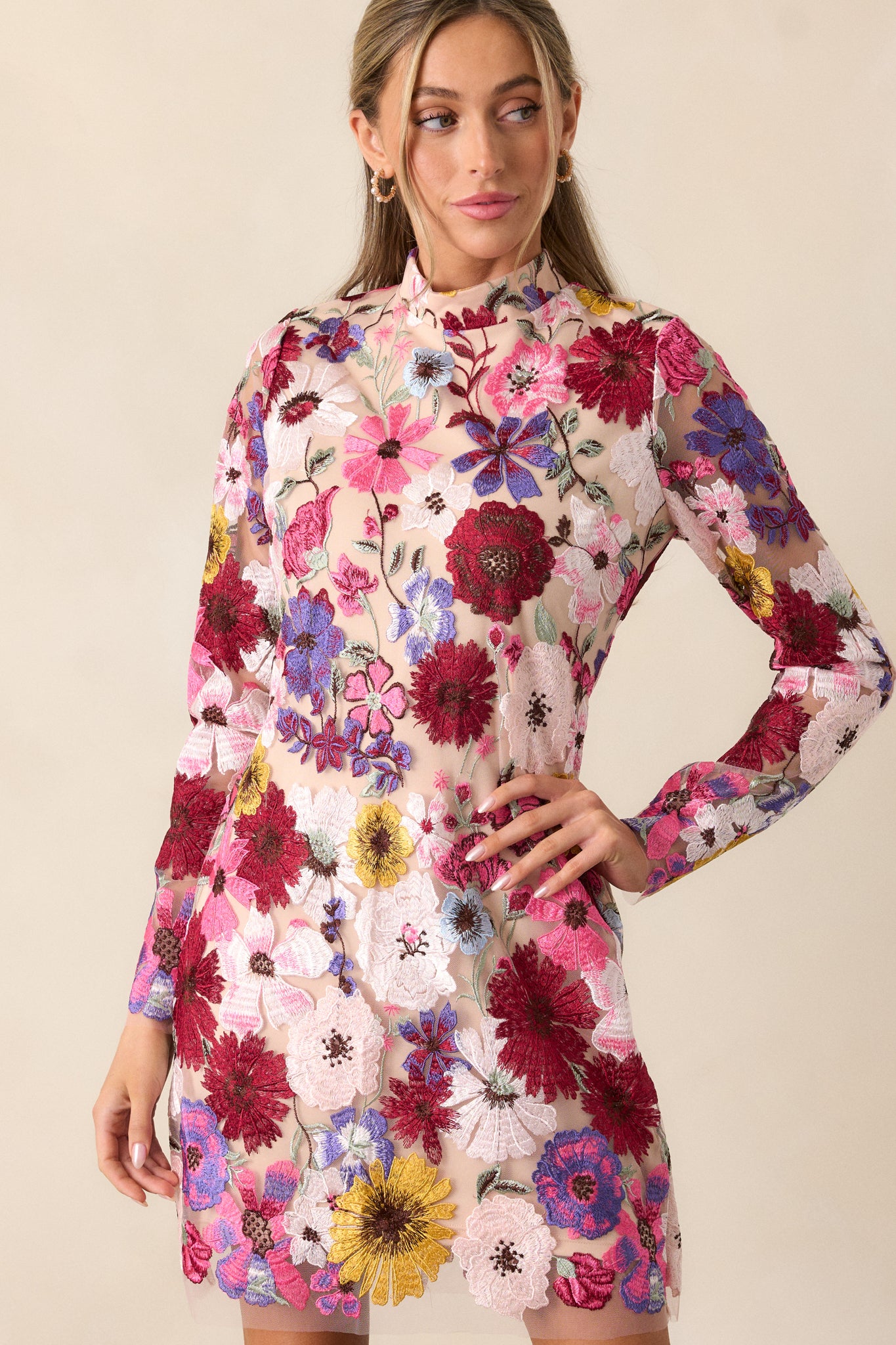 Side view of the dress, showcasing the sheer floral overlay on the bodice, the fitted design, and the mini length with the sheer long sleeves.