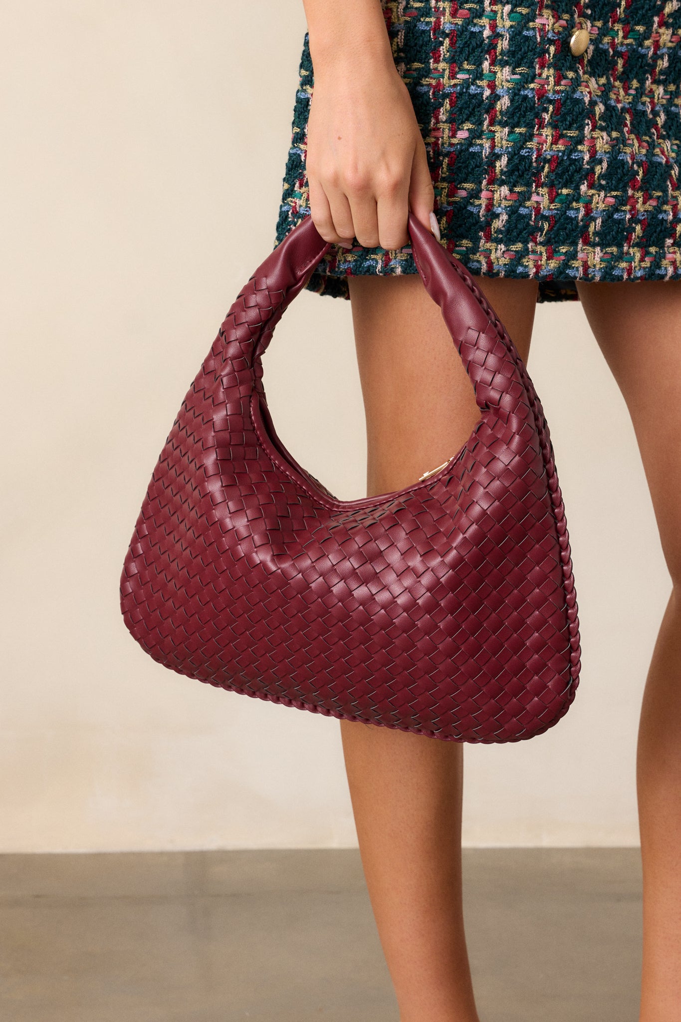 Full view of the wine handbag with a tight woven texture, solid faux leather handle, and gold zipper closure.