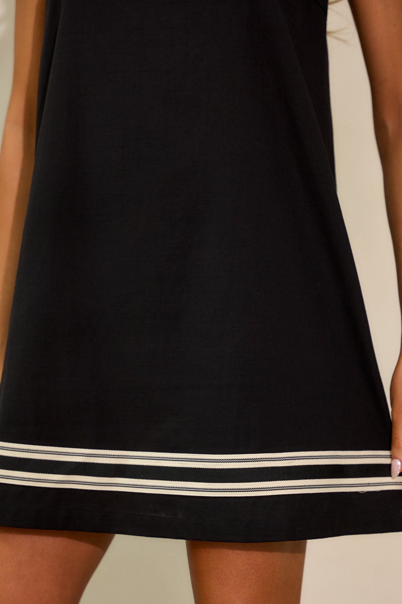 A closer view of the contrast stripe detailing near the bottom hem of the dress, highlighting the neat stitching and crisp lines.