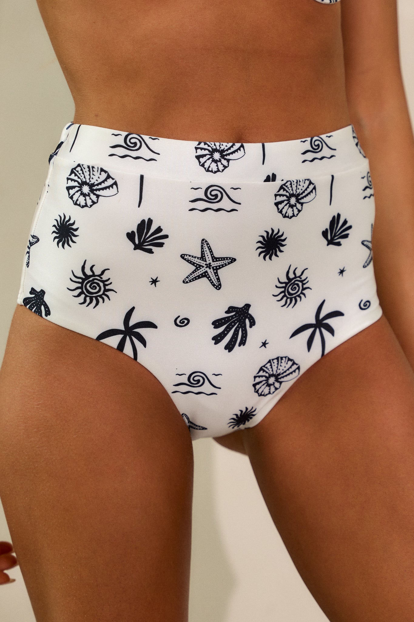 Close-up front view of the bikini bottoms, focusing on the tropical shell print and high-waist fit.