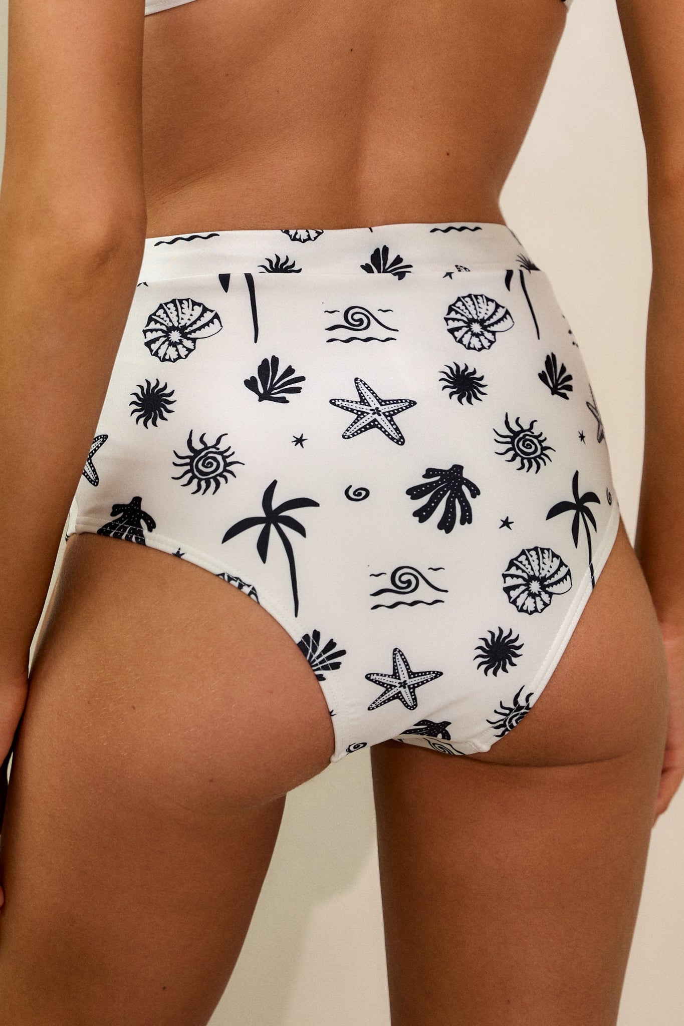 Back view of the bikini bottoms, showing the cheeky backside design and high-waisted cut with the tropical shell print.