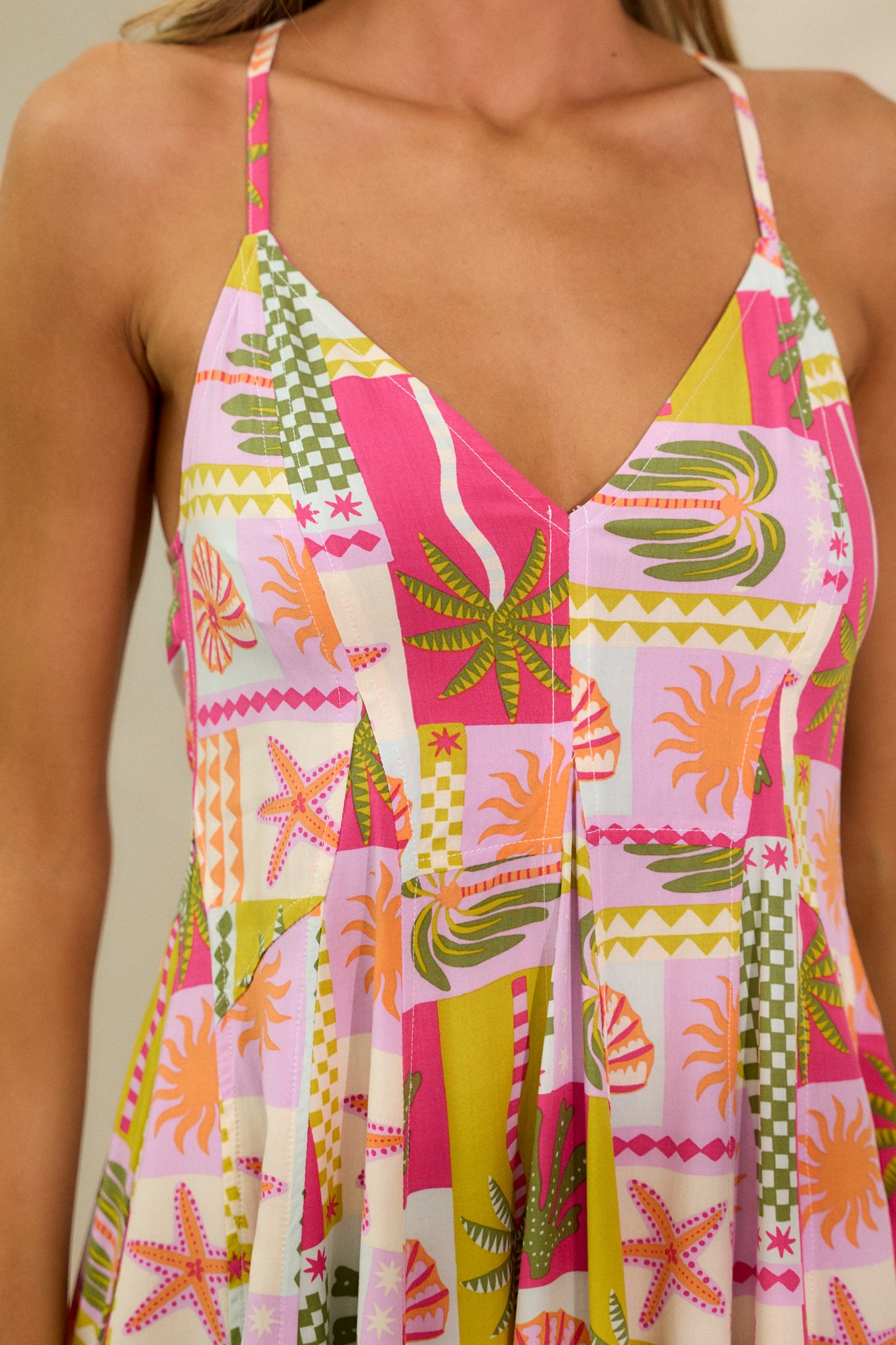 Close-up of the vibrant under the sea print on the pink mini dress, focusing on the fabric texture and design details, with the v-neckline visible.