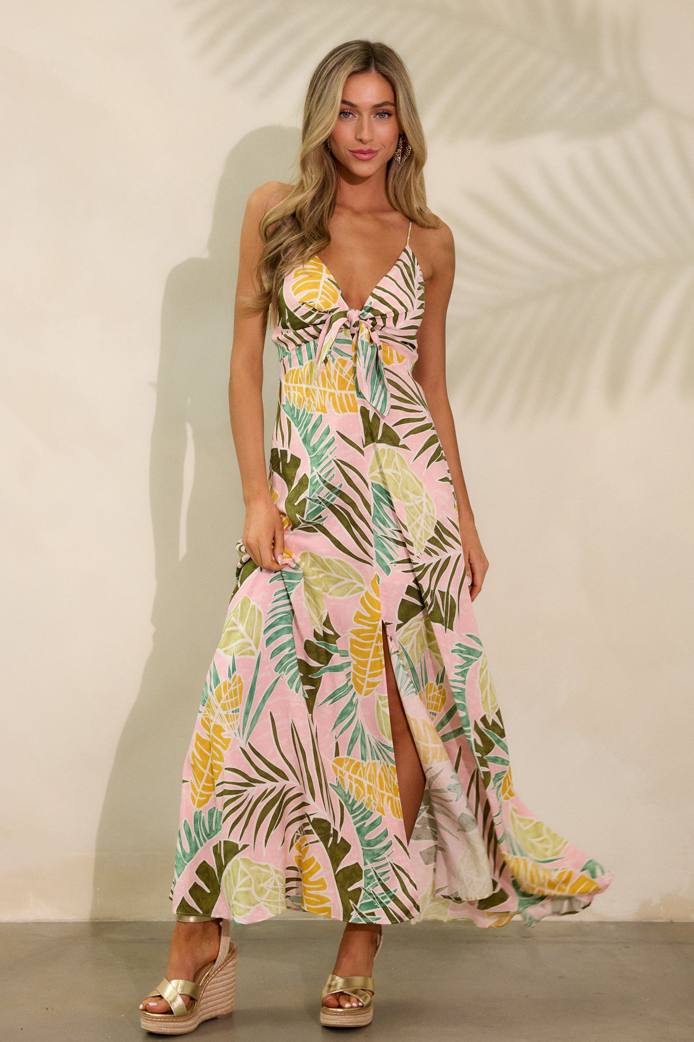 Another front shot of the light pink maxi dress emphasizing the adjustable straps, front slit, and the unique palm pattern on the flowing silhouette.