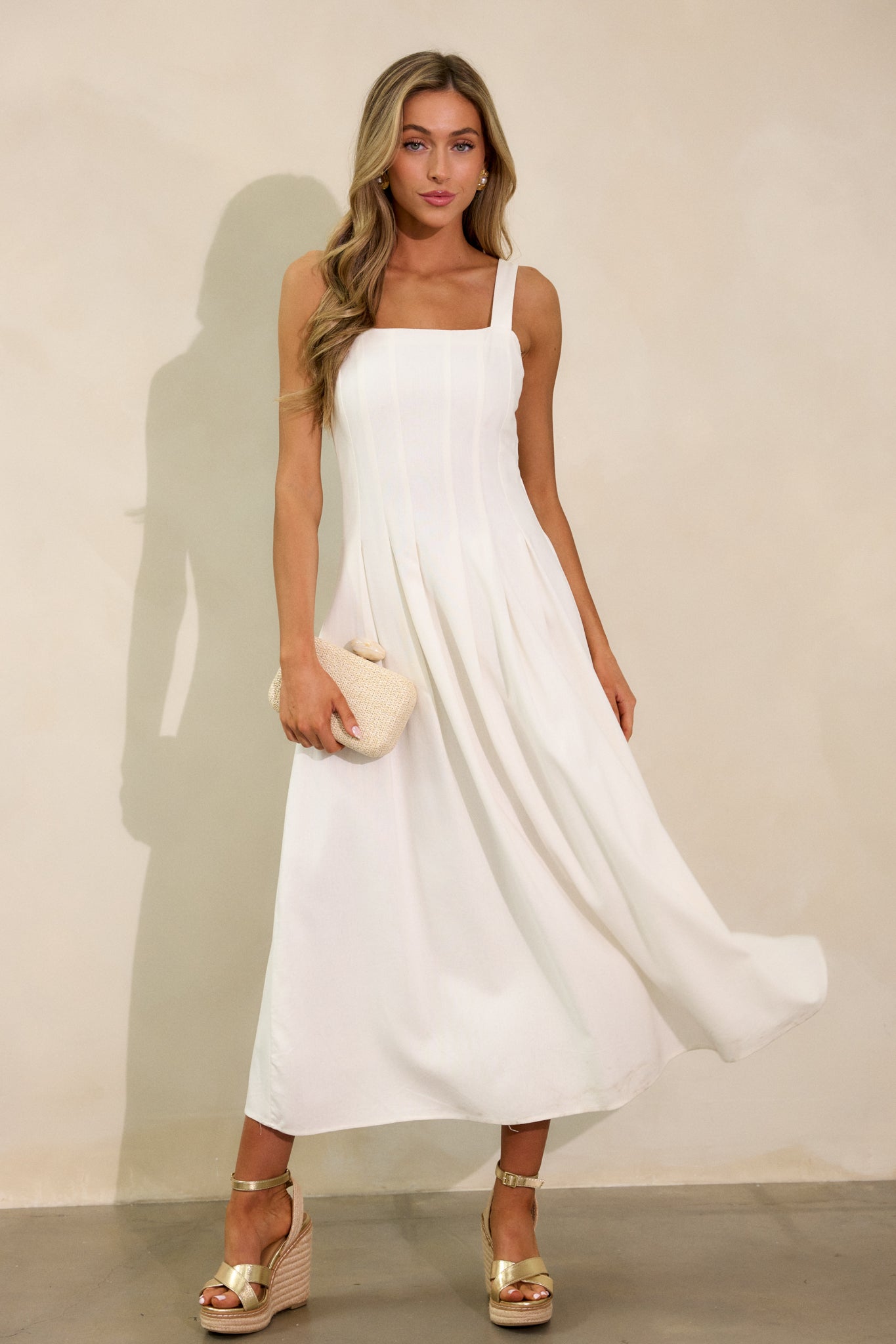 The ivory dress with a square neckline and sleeveless design, captured in a relaxed pose. The back smock insert creates a subtle fitted look while the flowing skirt cascades softly.