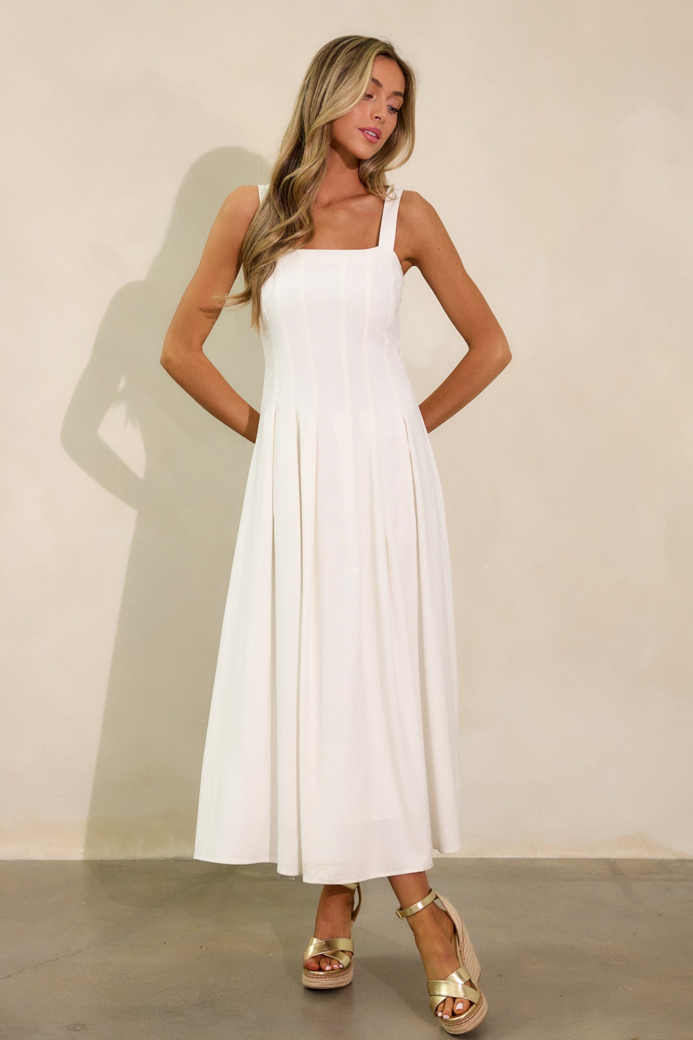 A full-body shot of the ivory dress with a square neckline and flowing silhouette, highlighting the soft movement of the fabric as it drapes naturally from the smocked back insert.