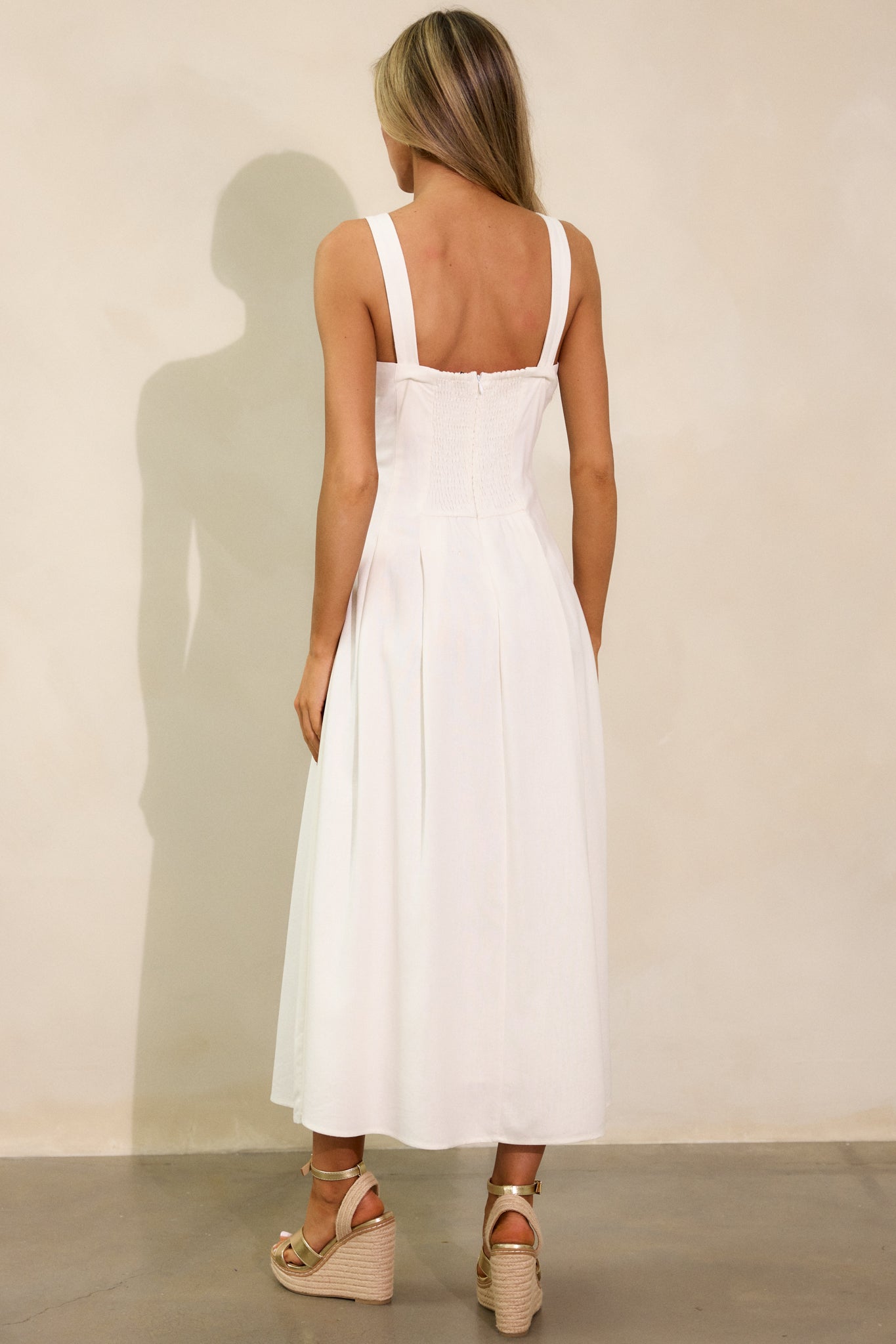 The back view of the ivory dress, showcasing the smock insert for a fitted effect and the discreet back zipper. The flowing silhouette of the dress is elegantly framed from behind.