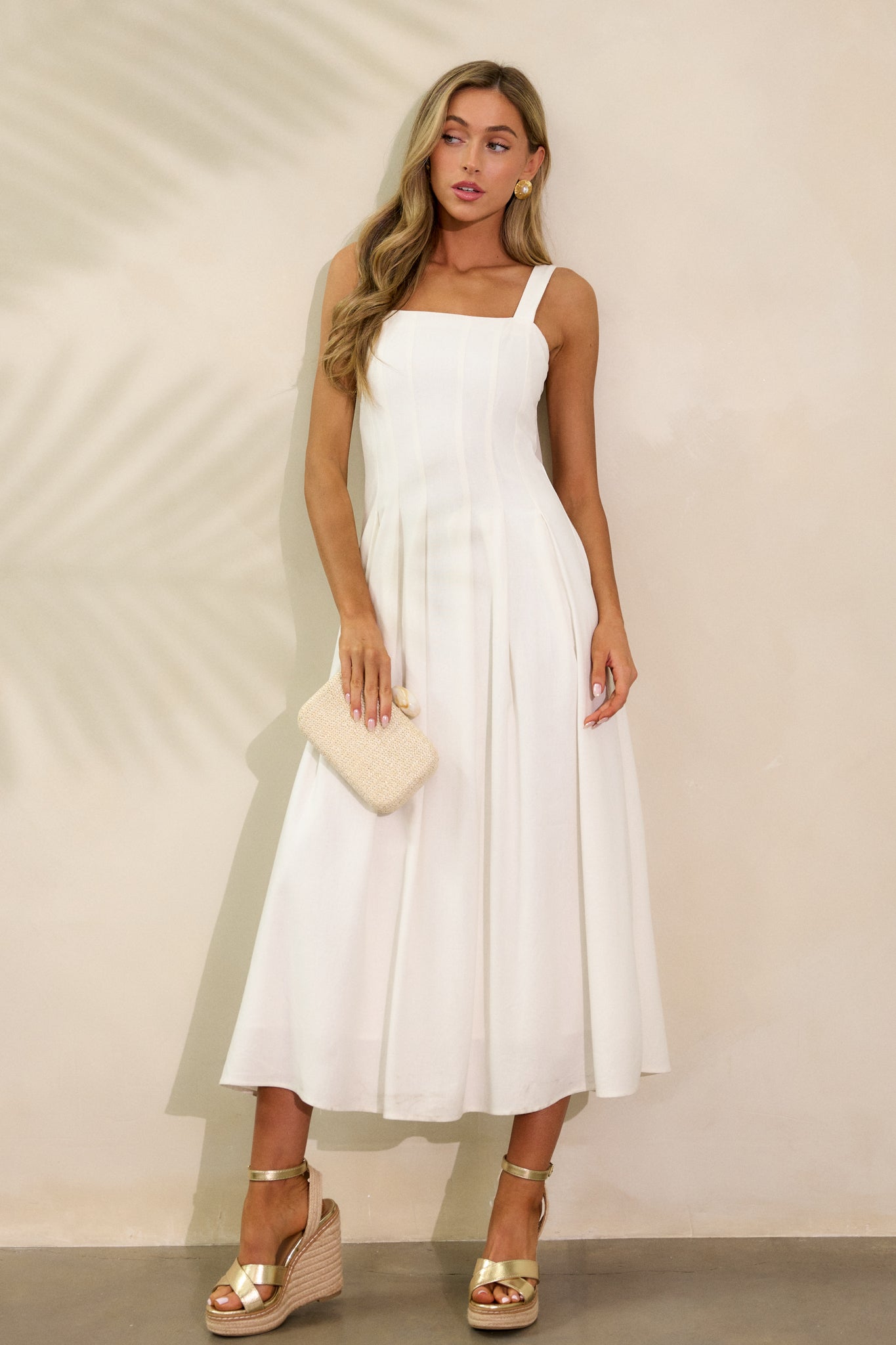 The ivory dress with a flowing skirt and square neckline, shown in a standing pose that emphasizes the light, fluid fabric. The sleeveless design offers a fresh, modern appeal.