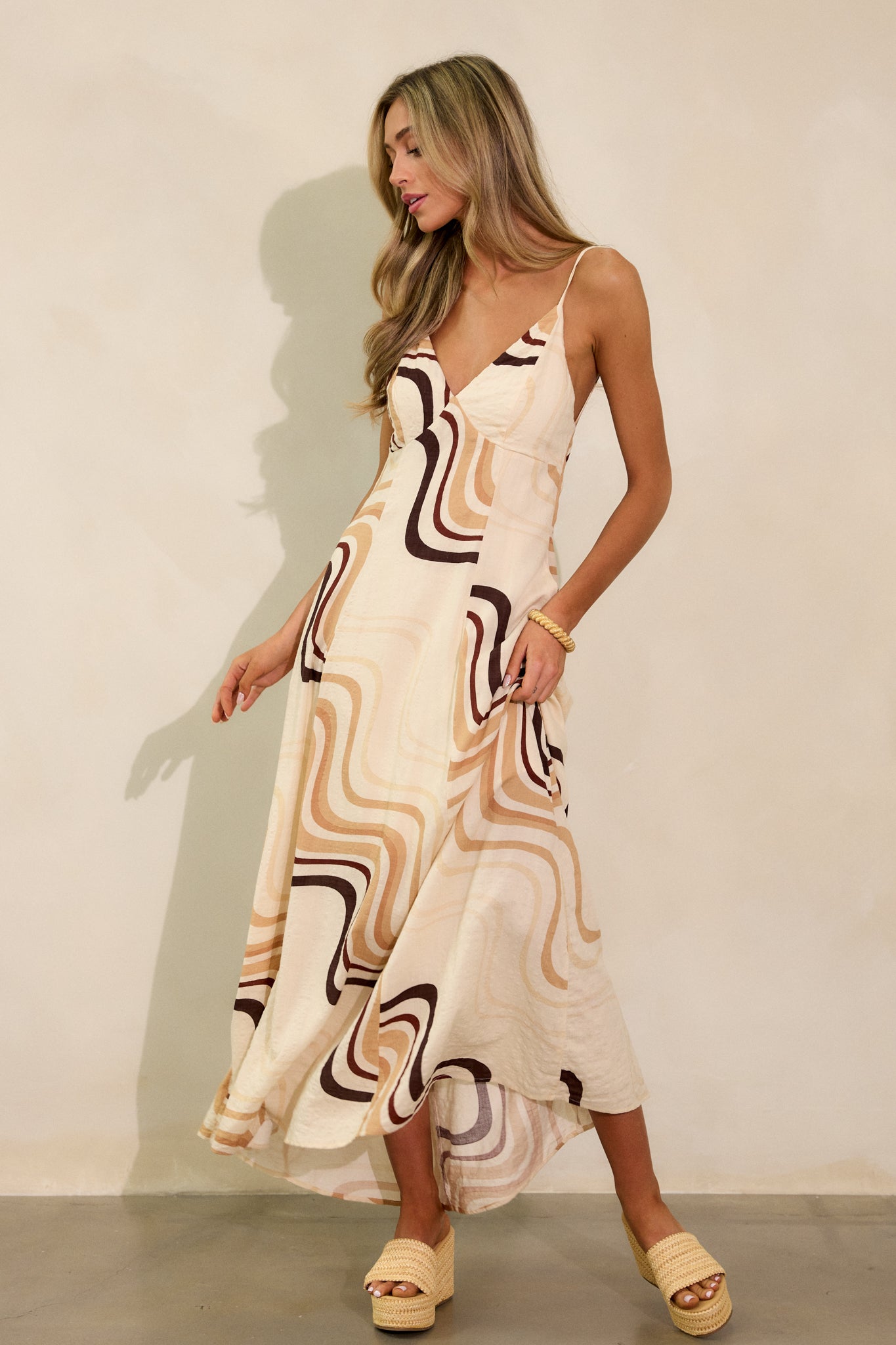 Another angle of the beige maxi dress showing the plunging neckline, pockets, and buttons down the back, with the unique print on display.