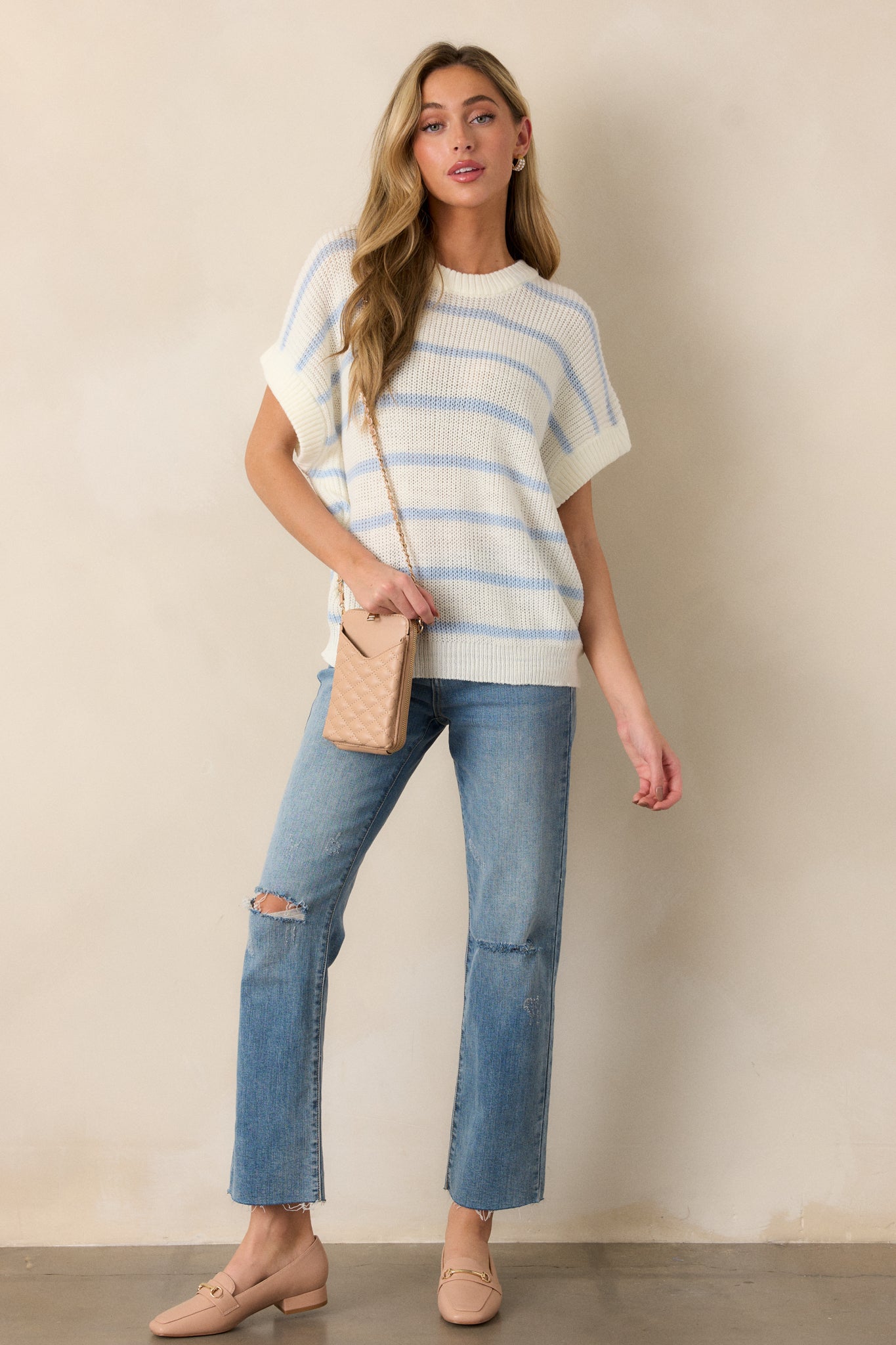 A full-length shot highlighting the sweater’s relaxed fit, short oversized sleeves, and the striped pattern. The rounded ribbed neckline frames the top, and the ribbed bottom hem completes the relaxed yet structured look.