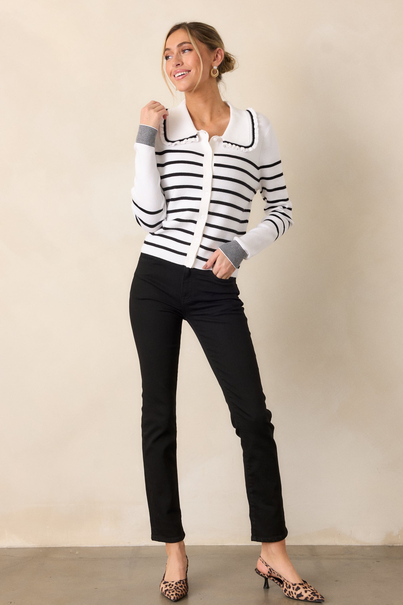 Front view of the white and black cardigan, highlighting the ruffled peter pan collar with black detailing and the button front design with a classic stripe pattern.