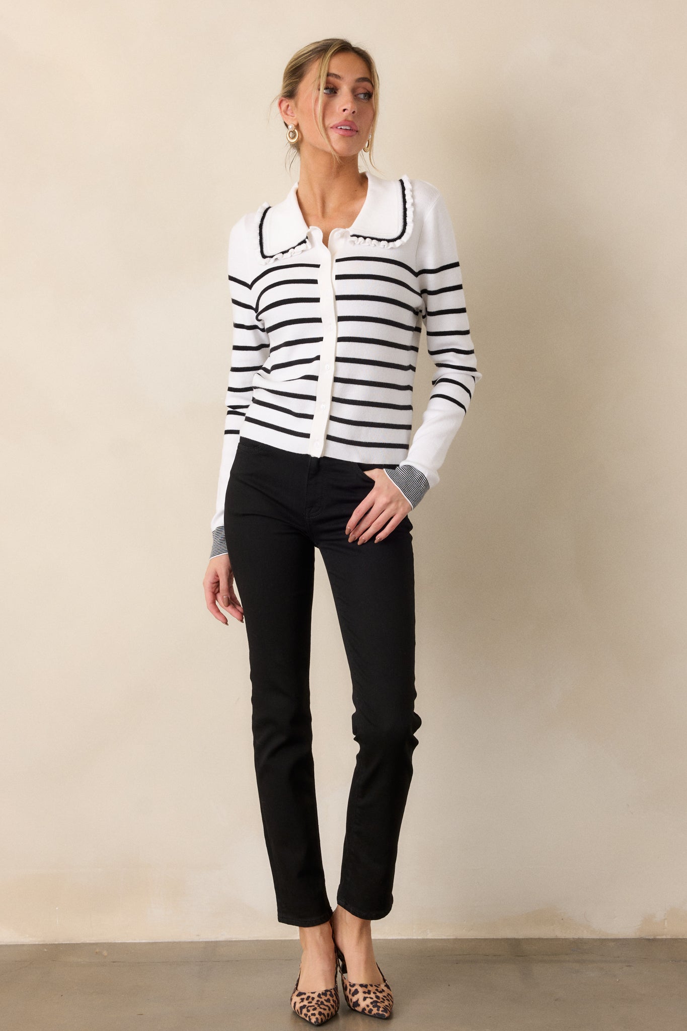 Full length view, capturing the full look of the cardigan, with the black-trimmed ruffled collar, button front, and balanced stripe pattern.