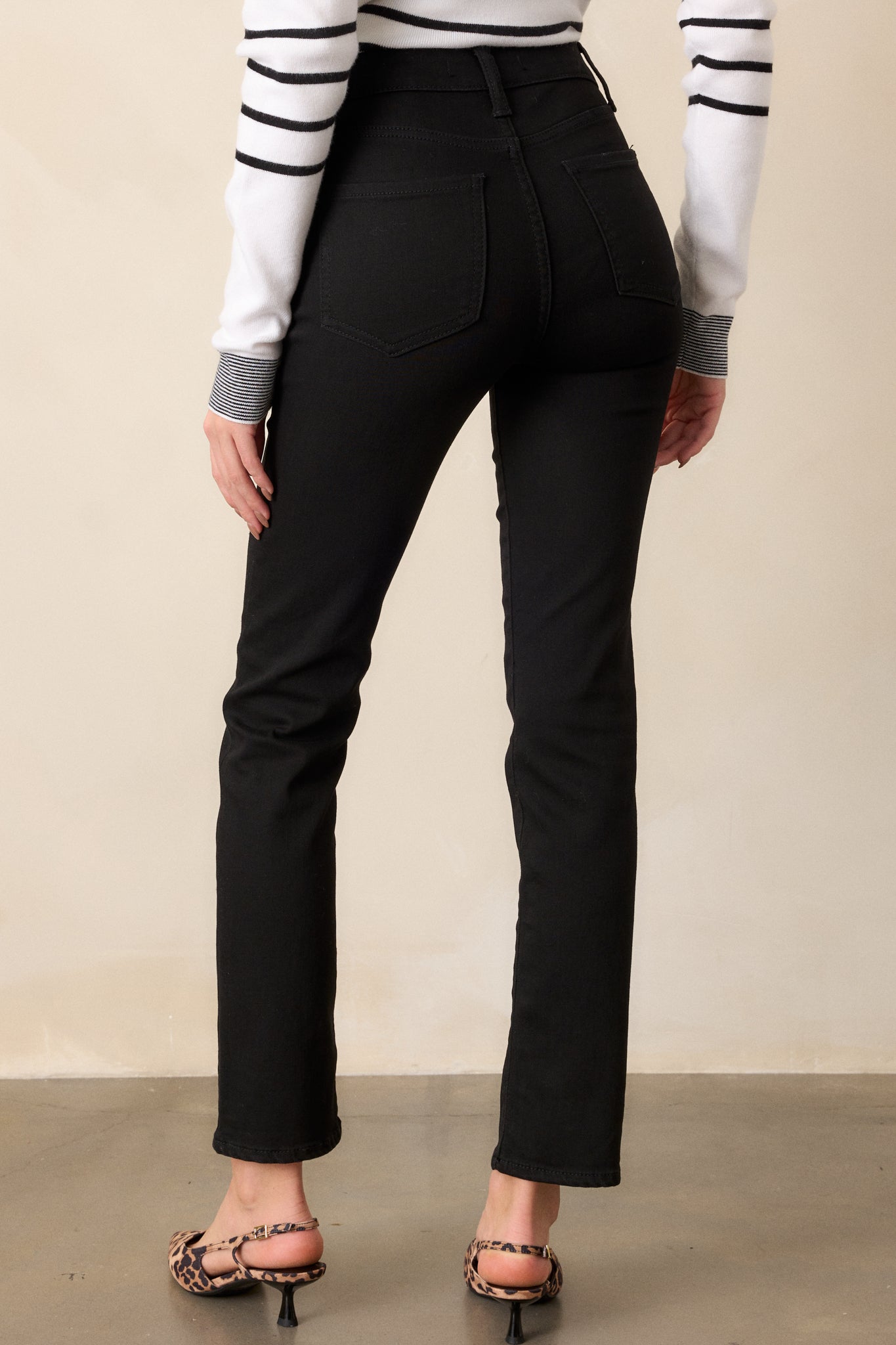 Back view of the black jeans, displaying the straight leg fit and the pocket placements, along with the smooth fabric finish.