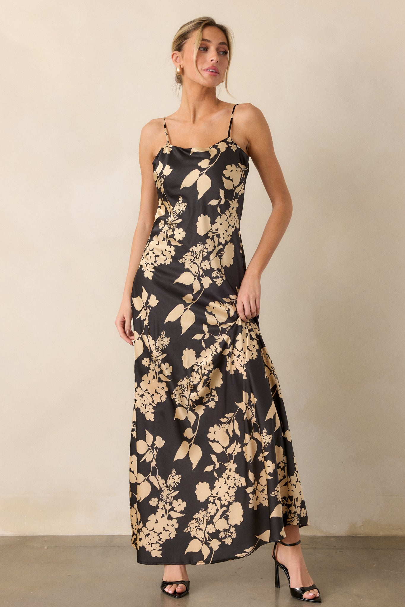 A front-facing view of the dress, highlighting the maxi length and the contrast between the black fabric and the gold floral design.