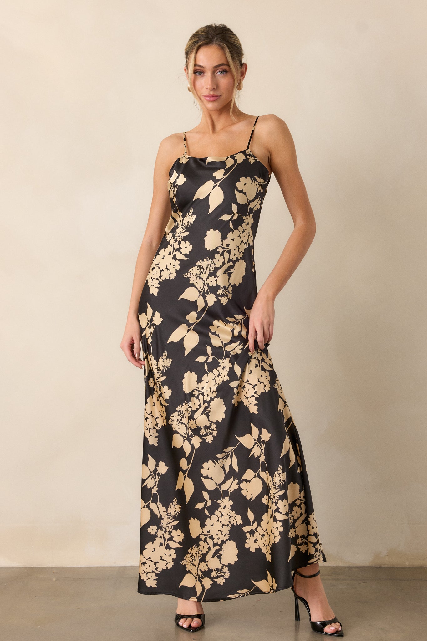 The dress displayed with its slightly curved neckline, emphasizing the intricate black and gold floral pattern across the bodice.