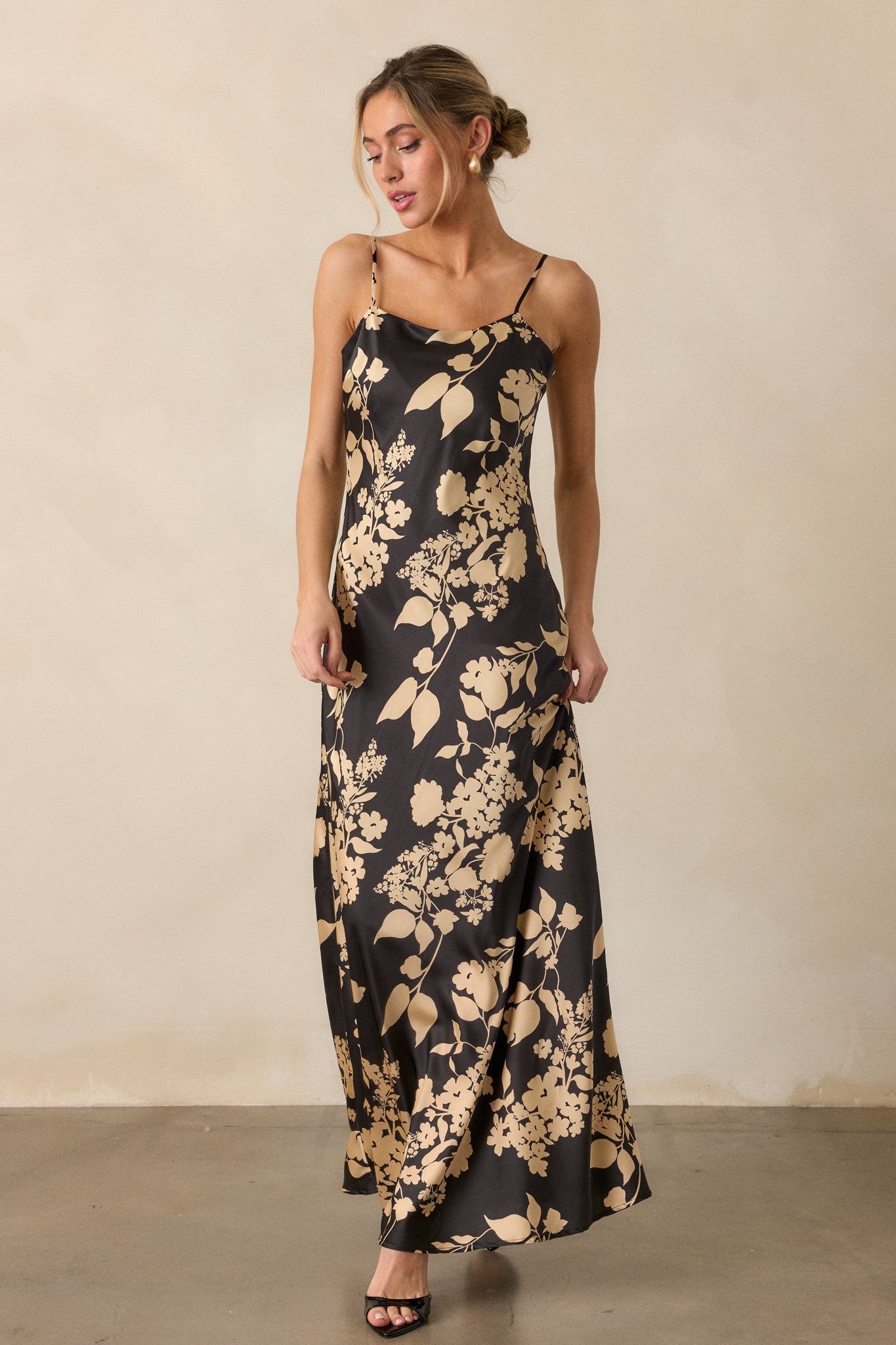 A front view of the dress, showing the sleeveless design and the way the black and gold floral pattern flows down the skirt.