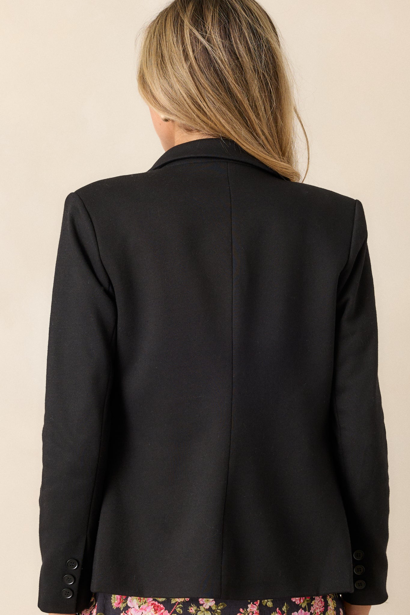 Back view of the black blazer showcasing the clean lines and the overall structure, emphasizing the padded shoulders.