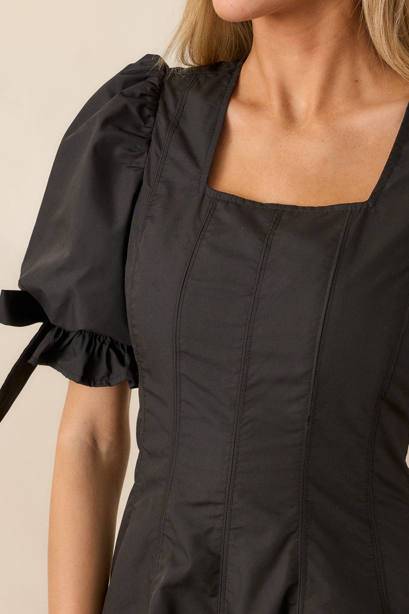 A close-up of the puff sleeves on the black dress, focusing on the smocked detailing and the bow accent.